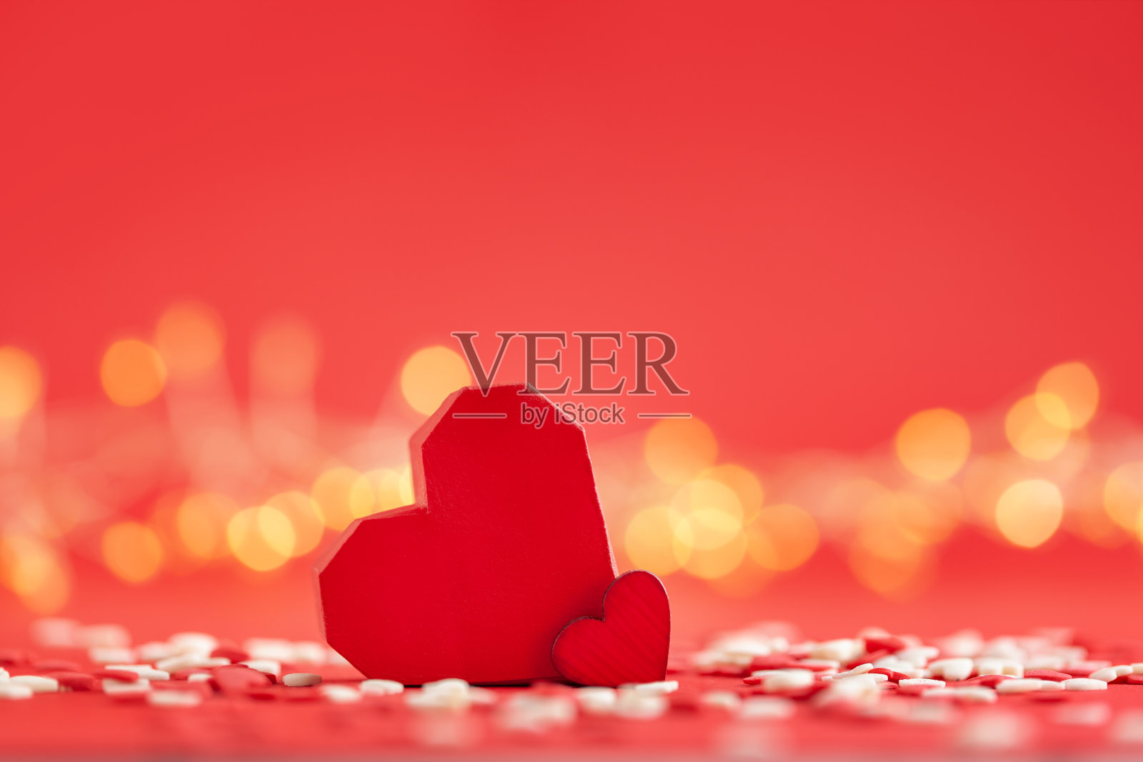 情人节创意贺卡。两个大大小小的红心在红色背景与节日散景。照片摄影图片