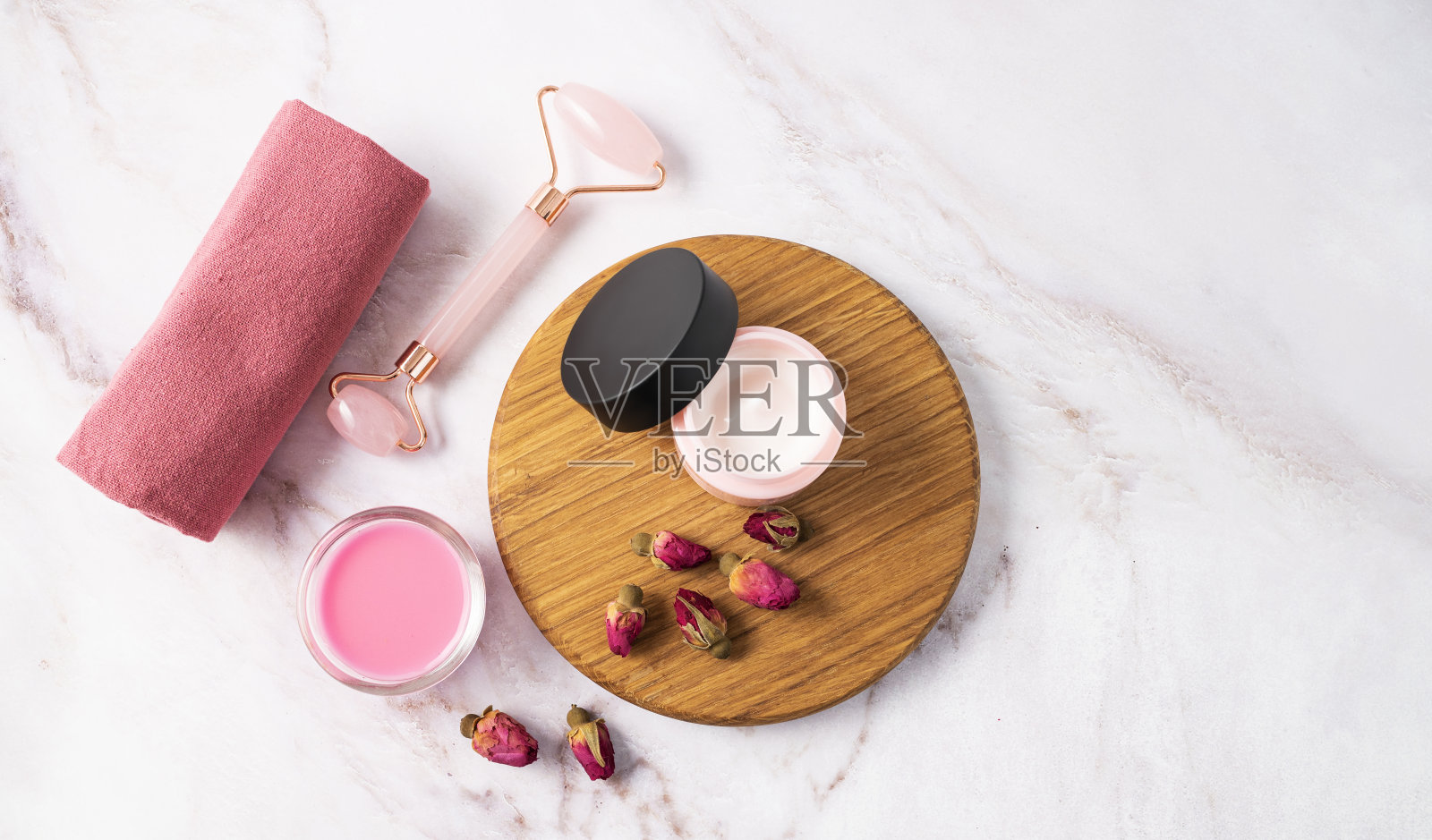 面霜、肥皂和按摩器放在大理石桌上。以玫瑰为概念的护理化妆品。健康与美丽。照片摄影图片