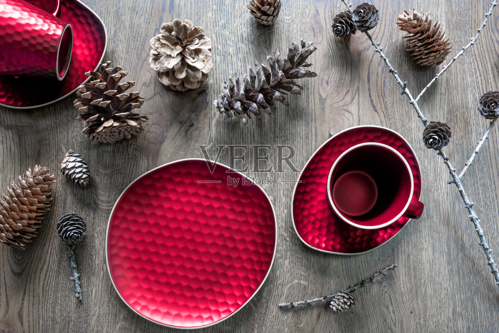一套红色的盘子:一个茶杯，碟子，盘子和木制背景上的各种各样的锥状物。圣诞餐桌装饰，神奇节日。照片摄影图片