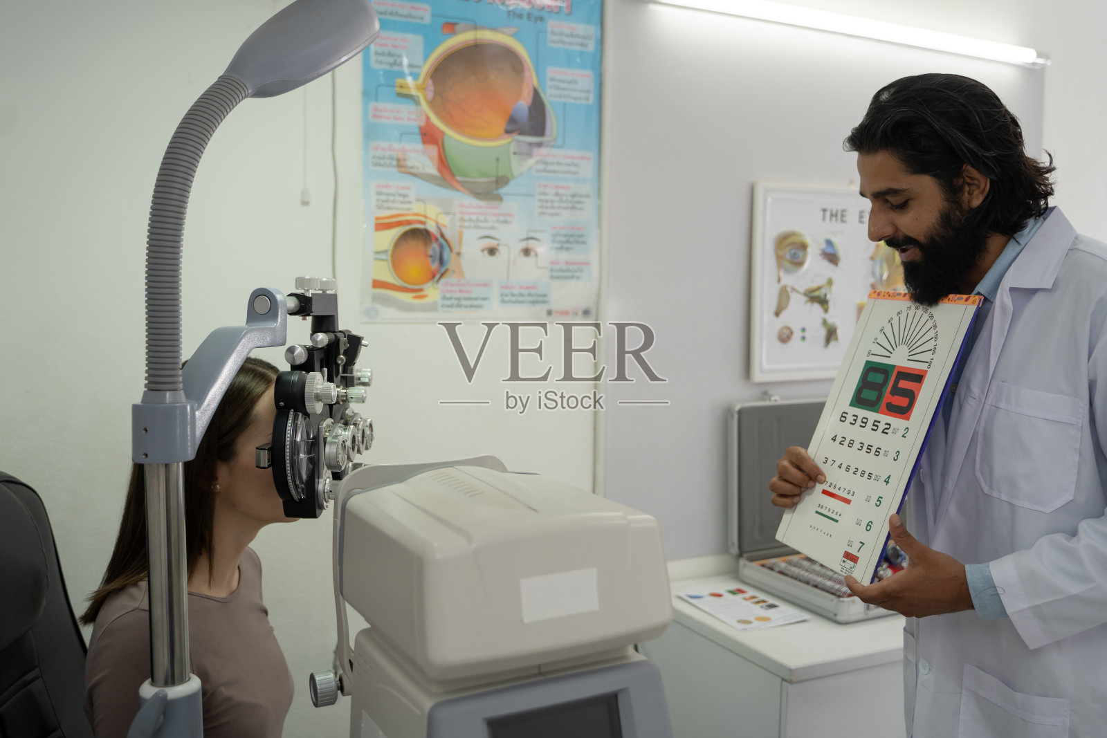 一位眼科医生在诊所用现代设备检查一位女病人。照片摄影图片