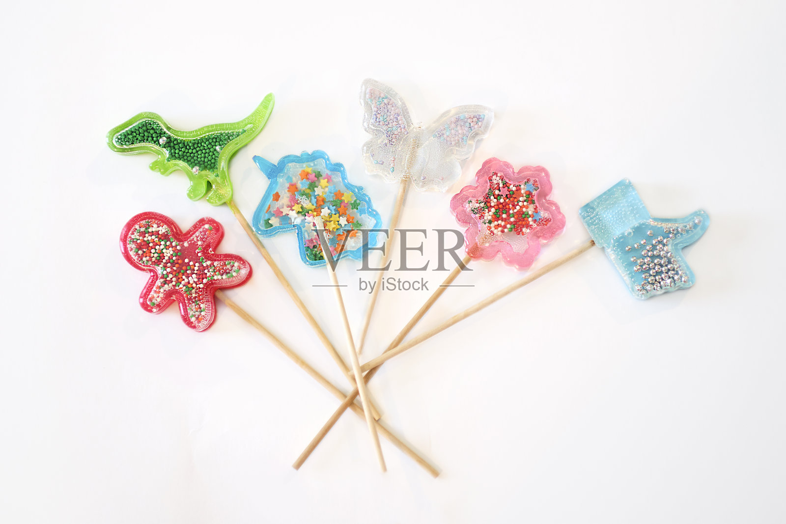 白色背景上的彩色棒棒糖。恐龙、独角兽、花朵和蝴蝶形状的漂亮棒棒糖照片摄影图片