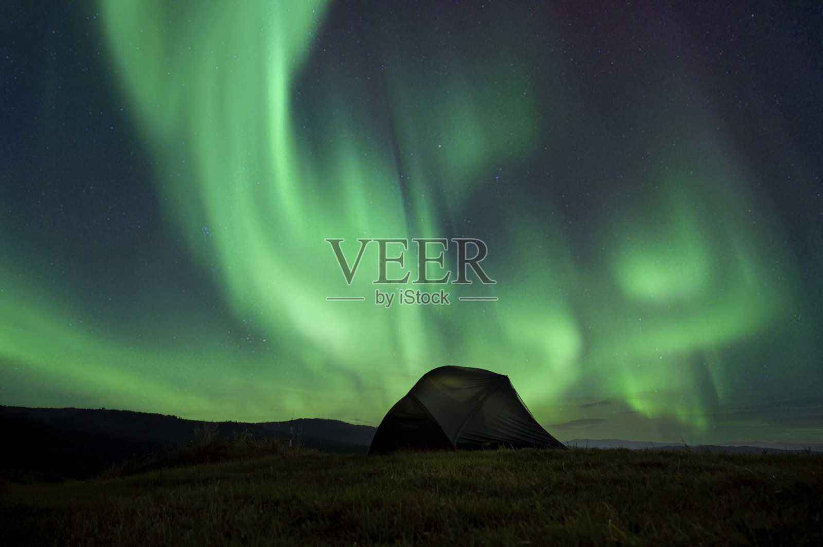 在引人注目的夜空下，山上的游客帐篷。山上五颜六色的日落。露营旅行概念。旅行者享受冒险的另类假期照片摄影图片