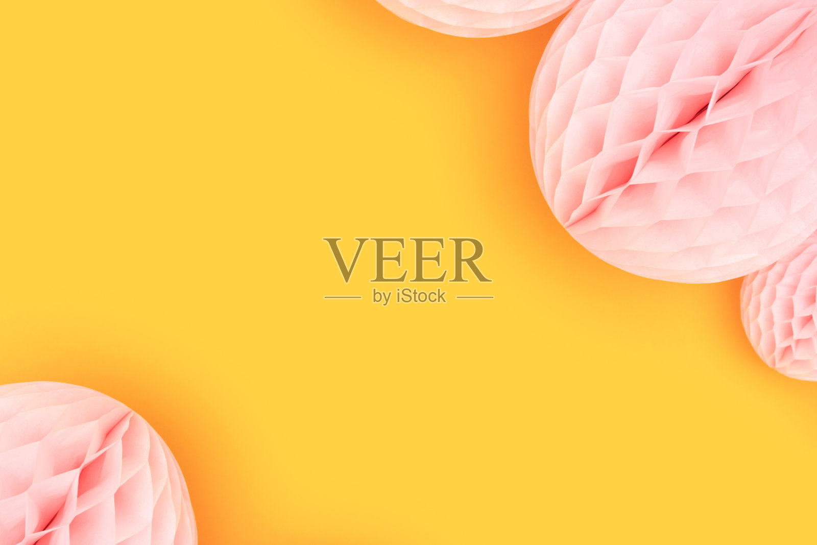 黄色背景的粉色纸球。照片摄影图片