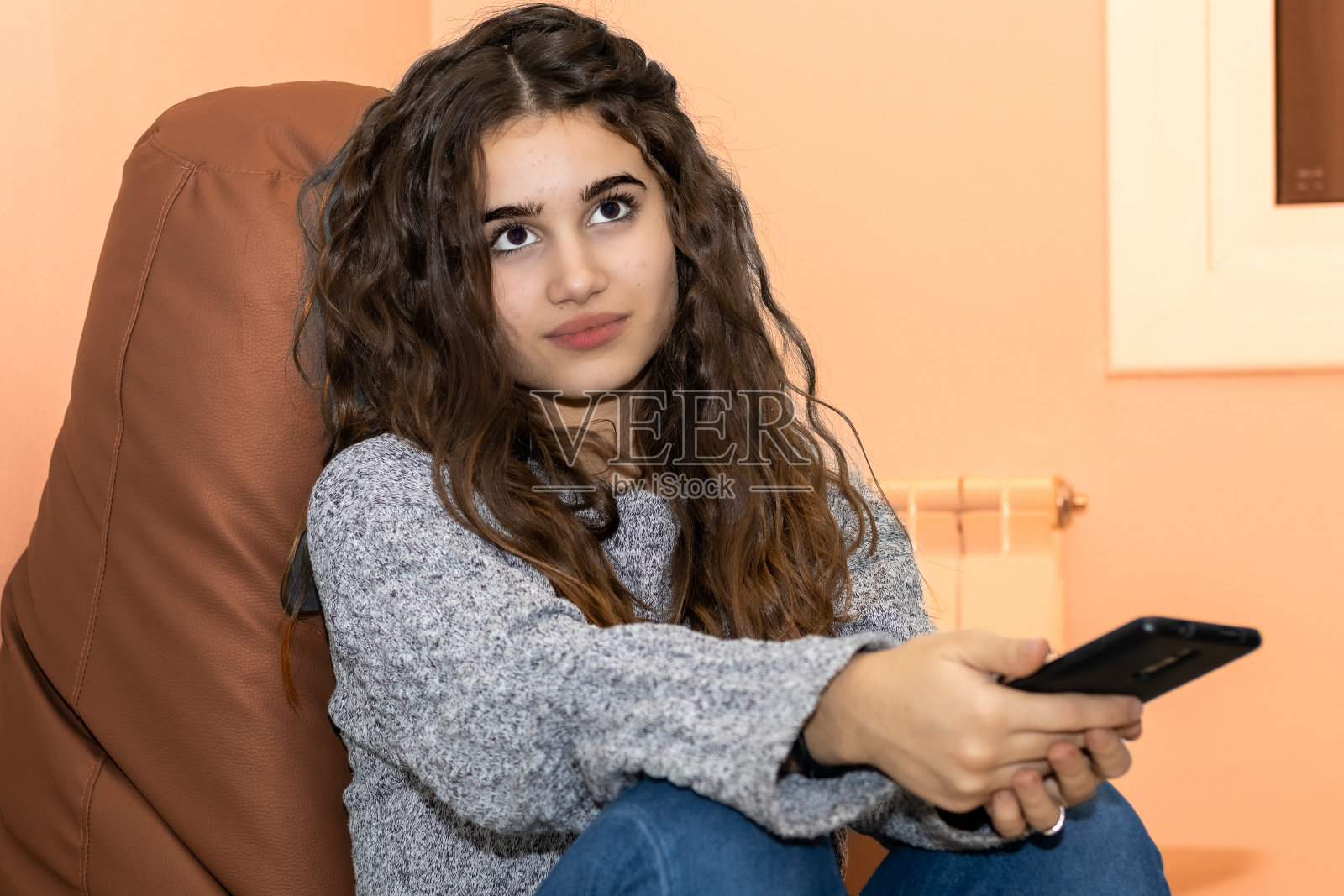 美丽的年轻女子在她的手机后思考照片摄影图片