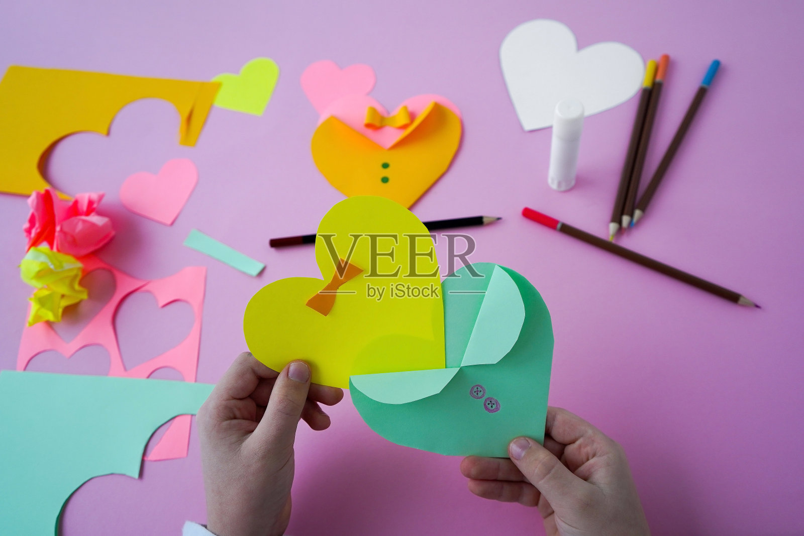 孩子手里拿着彩纸自制的节日贺卡、心形卡片作为情人节礼物照片摄影图片