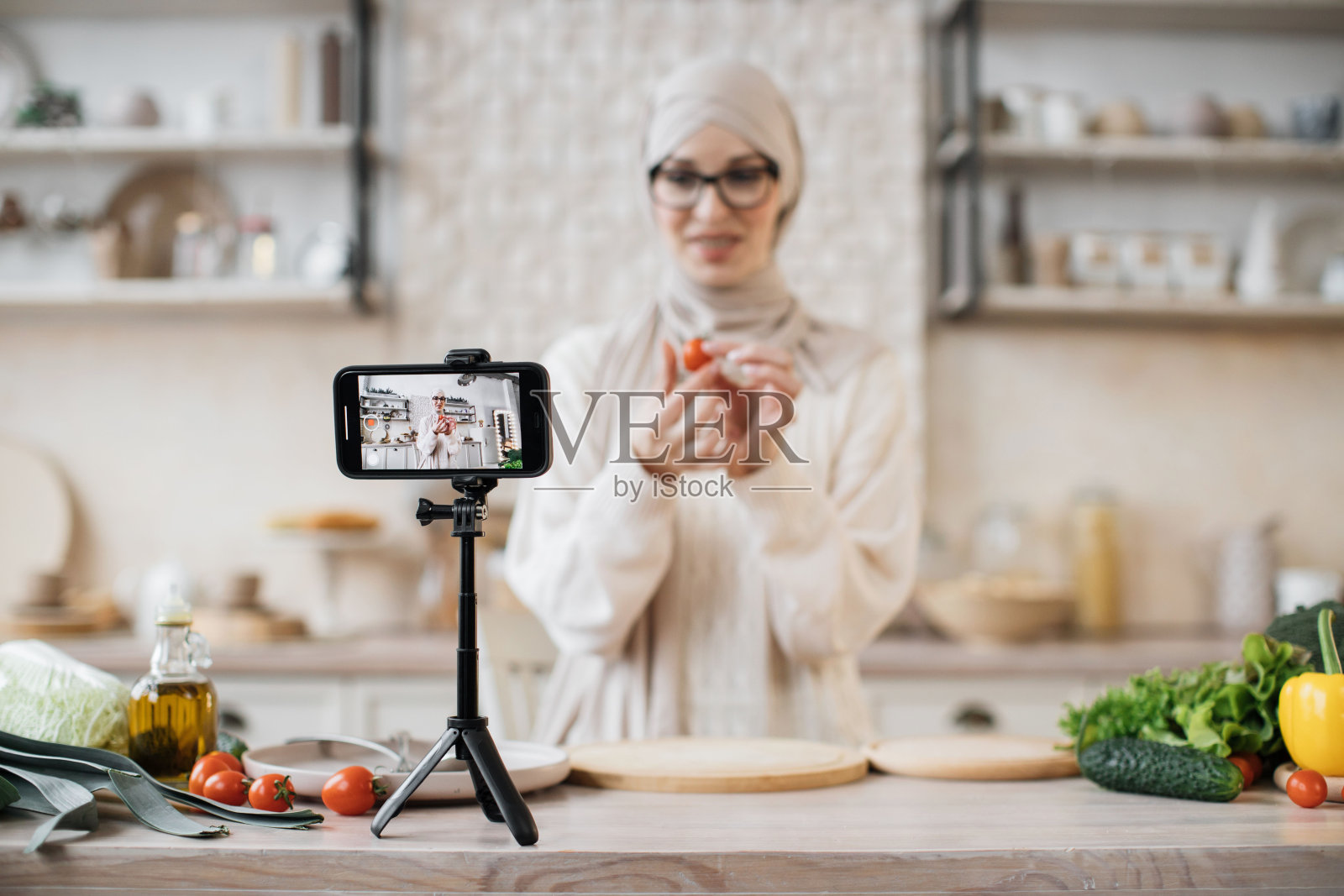 专注于智能手机，穿着休闲装和头巾的漂亮穆斯林女博主正在录制在线视频照片摄影图片