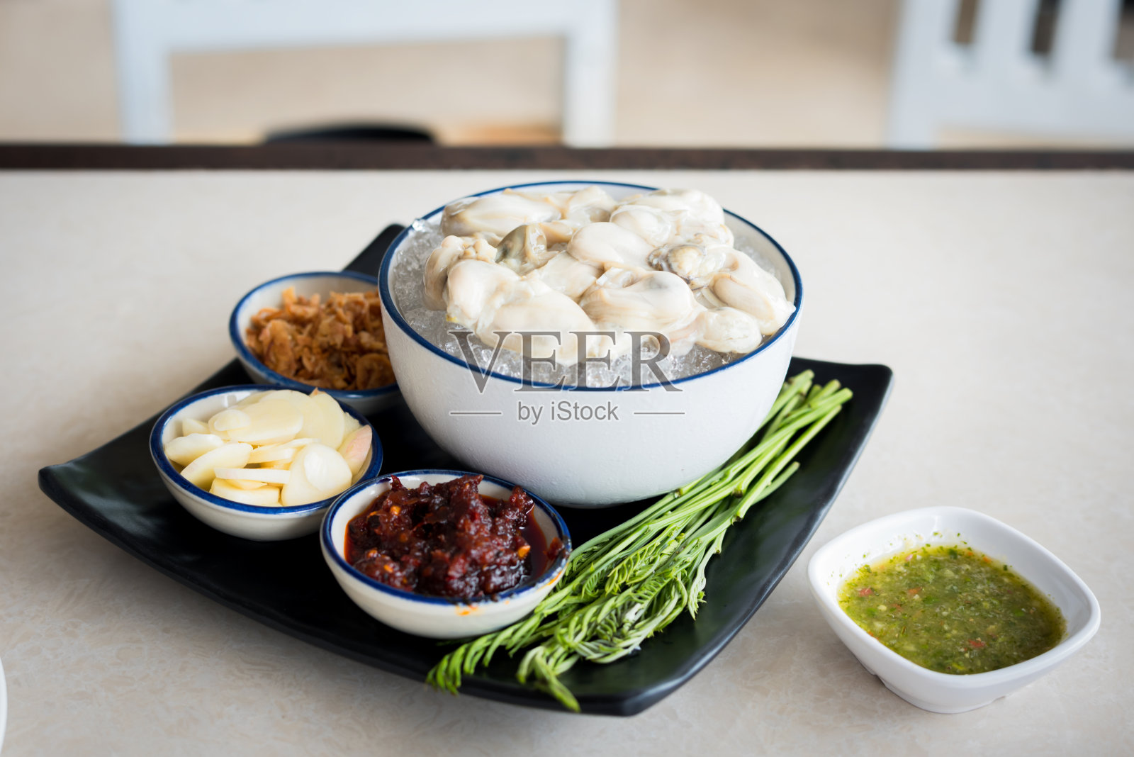 在泰国的海鲜餐厅，新鲜的冰生蚝配上辣酱。照片摄影图片