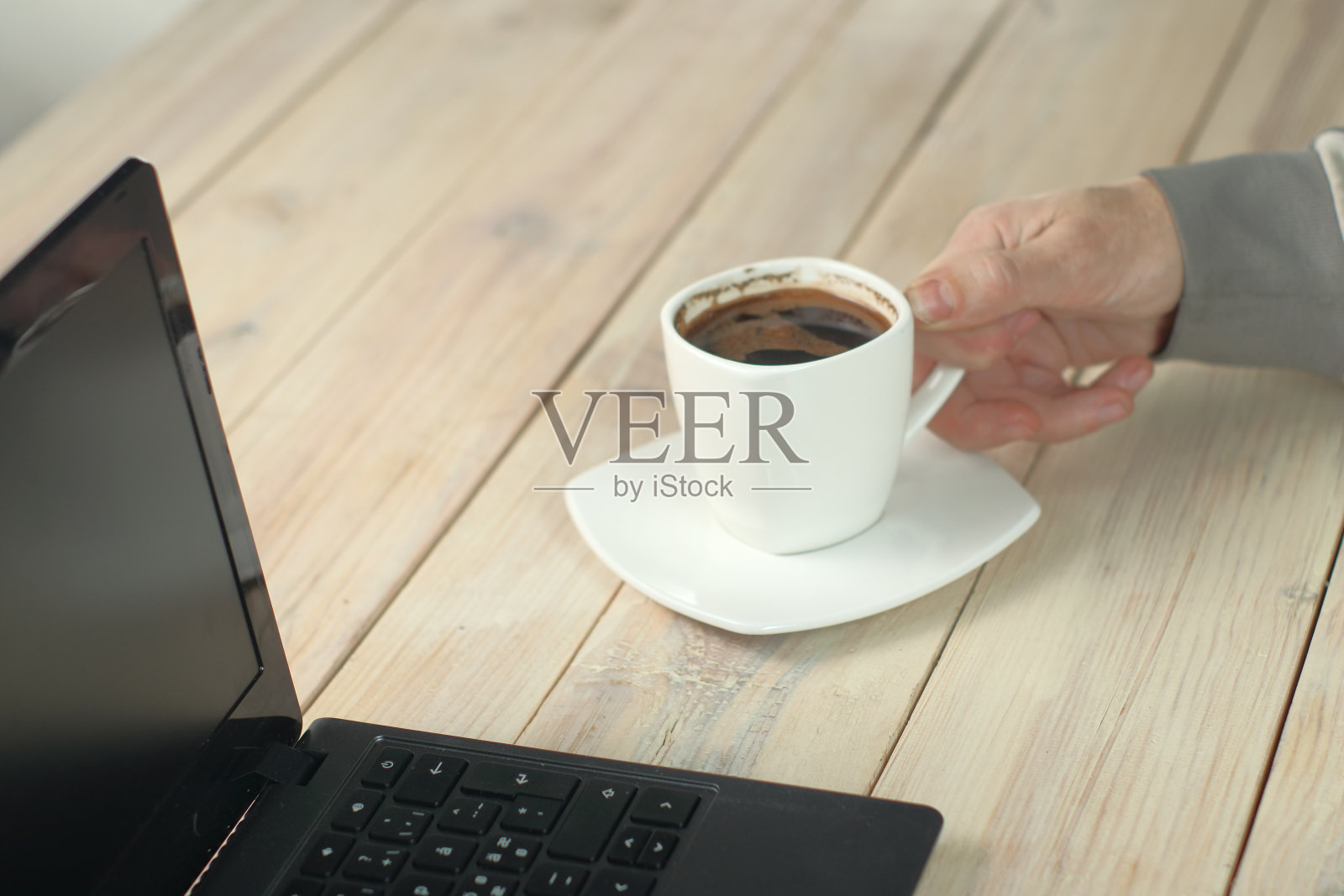 坐在笔记本电脑前喝咖啡的人照片摄影图片