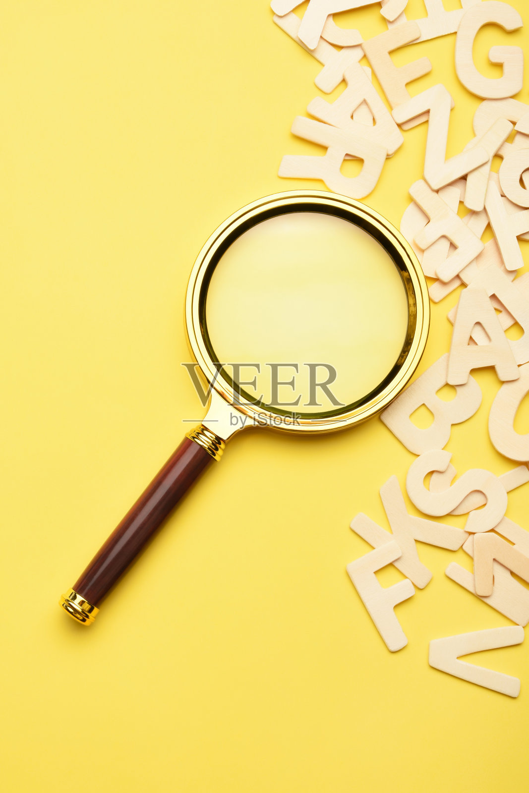 黄色背景上有木制字母的放大镜照片摄影图片