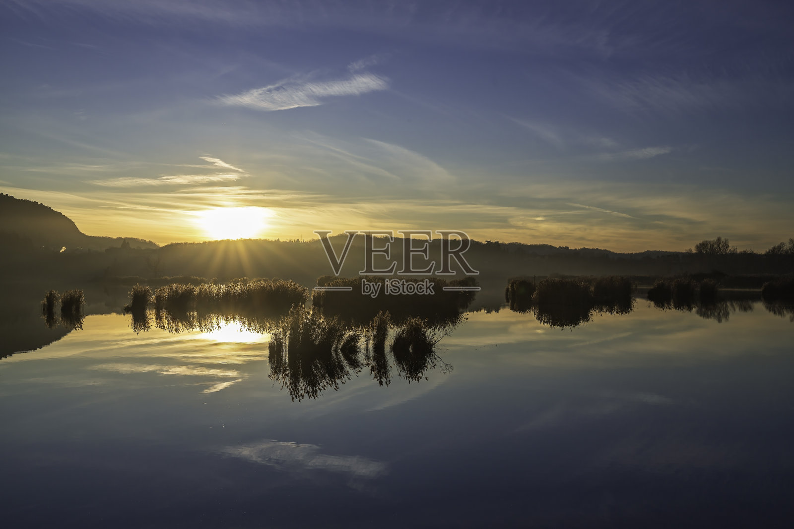 太阳从意大利伦巴第Torbiere del Sebino自然保护区的山上升起照片摄影图片