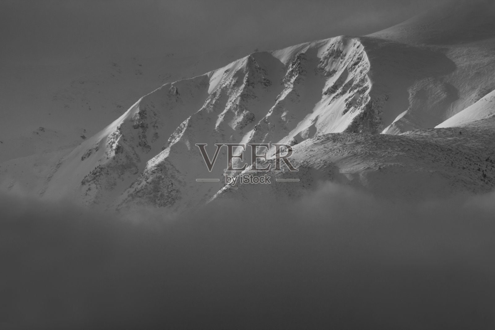 引人注目的冬季山地景观。白雪覆盖的朦胧的山峰和山丘。黑白照片。自然概念背景。照片摄影图片