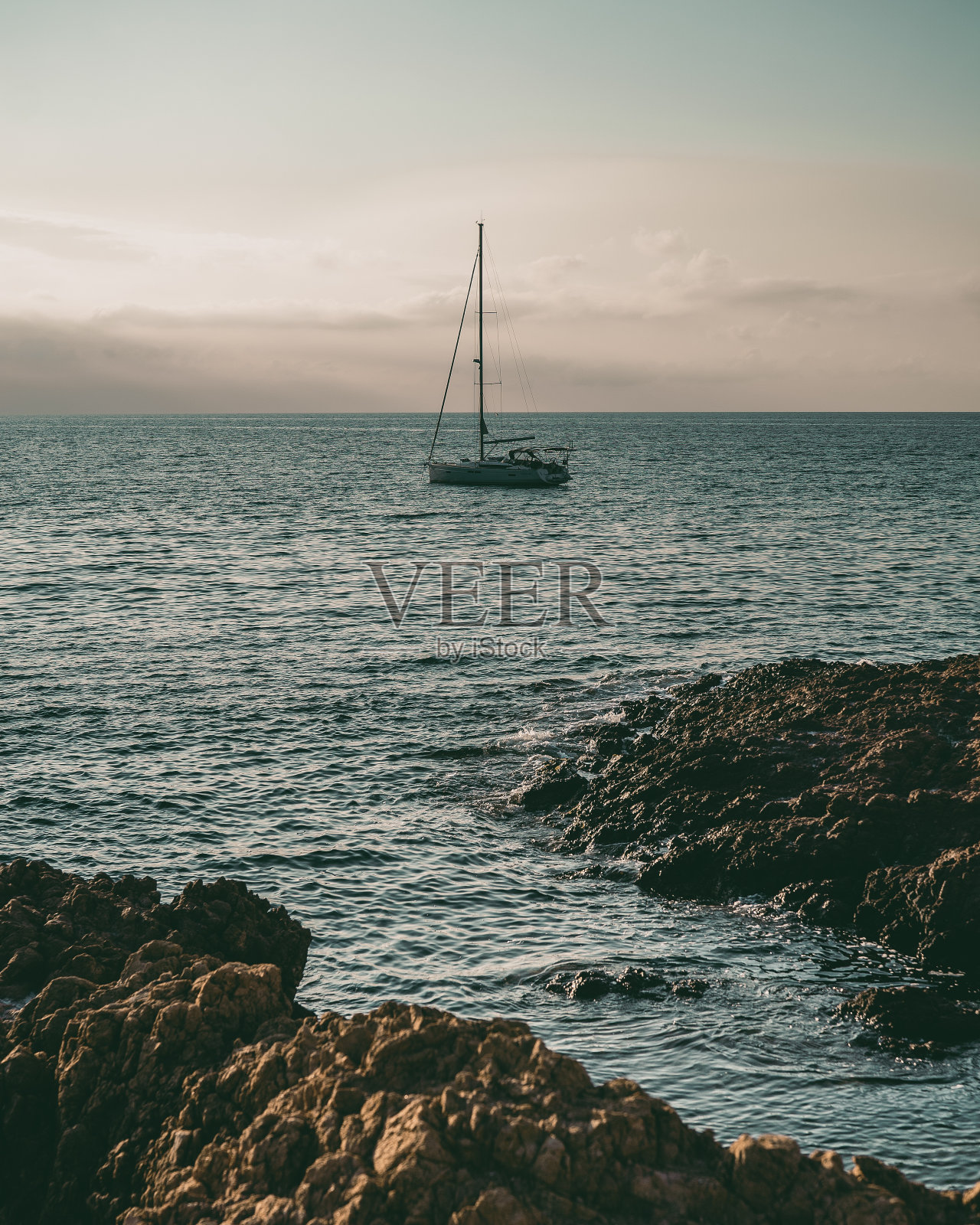 在法国里维埃拉多云日落的天空下，船在水中照片摄影图片