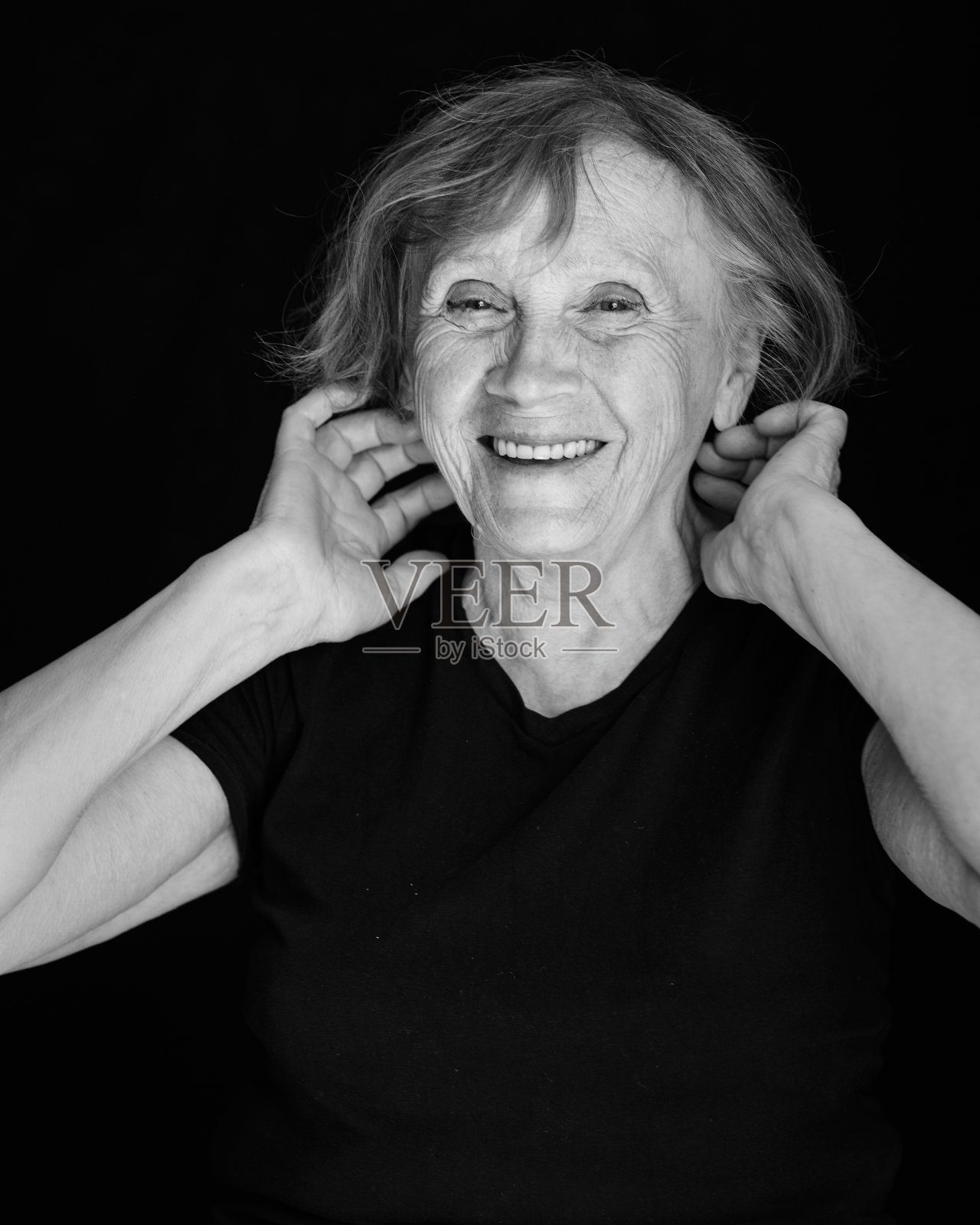 在黑色背景上的老年微笑的白人妇女的手的肖像照片摄影图片