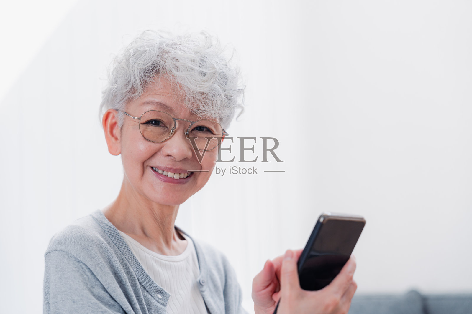 一位老妇人微笑着用她的智能手机照片摄影图片