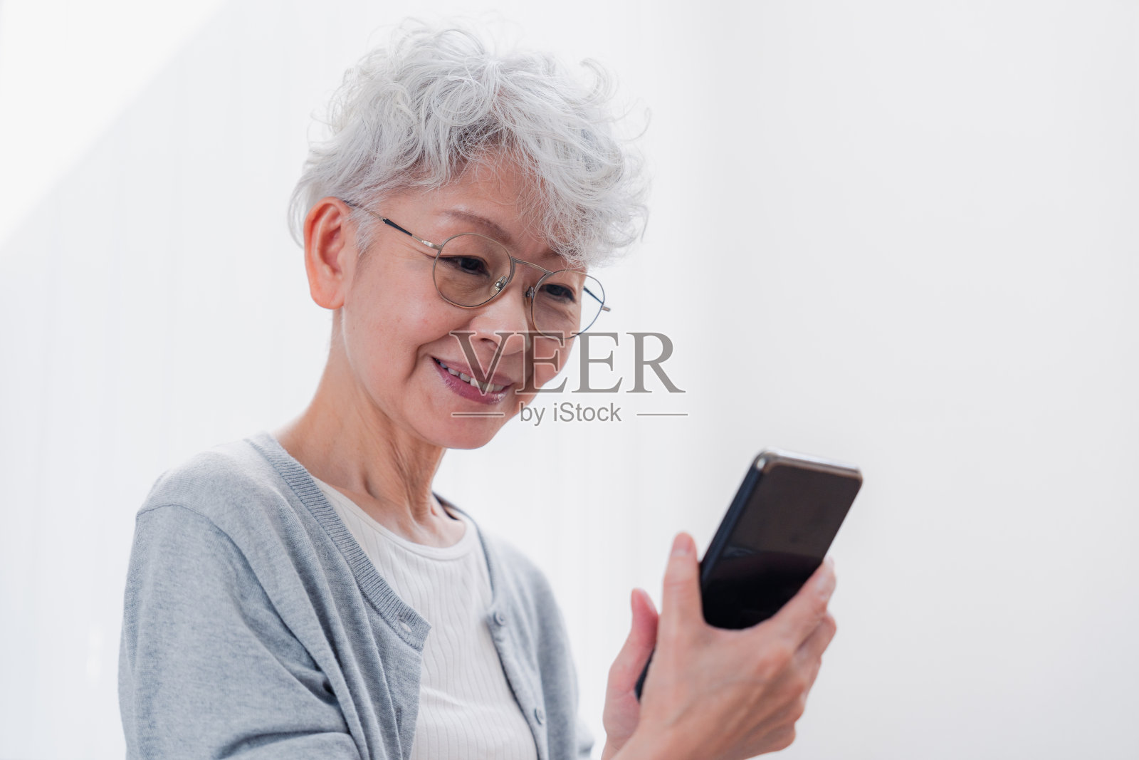 一位老妇人微笑着用她的智能手机照片摄影图片