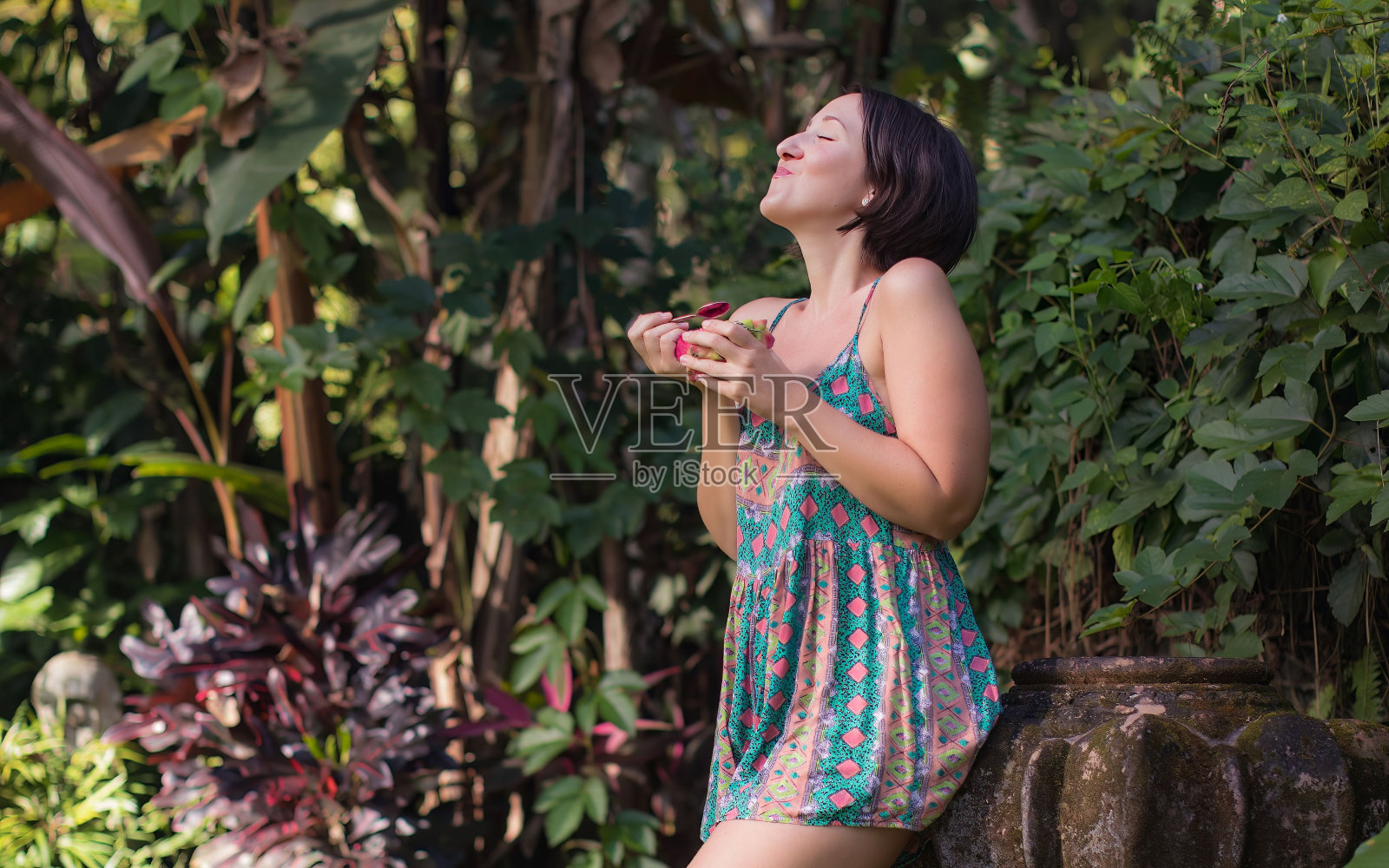夏天的一天，年轻的女性在公园里享受她的火龙果照片摄影图片