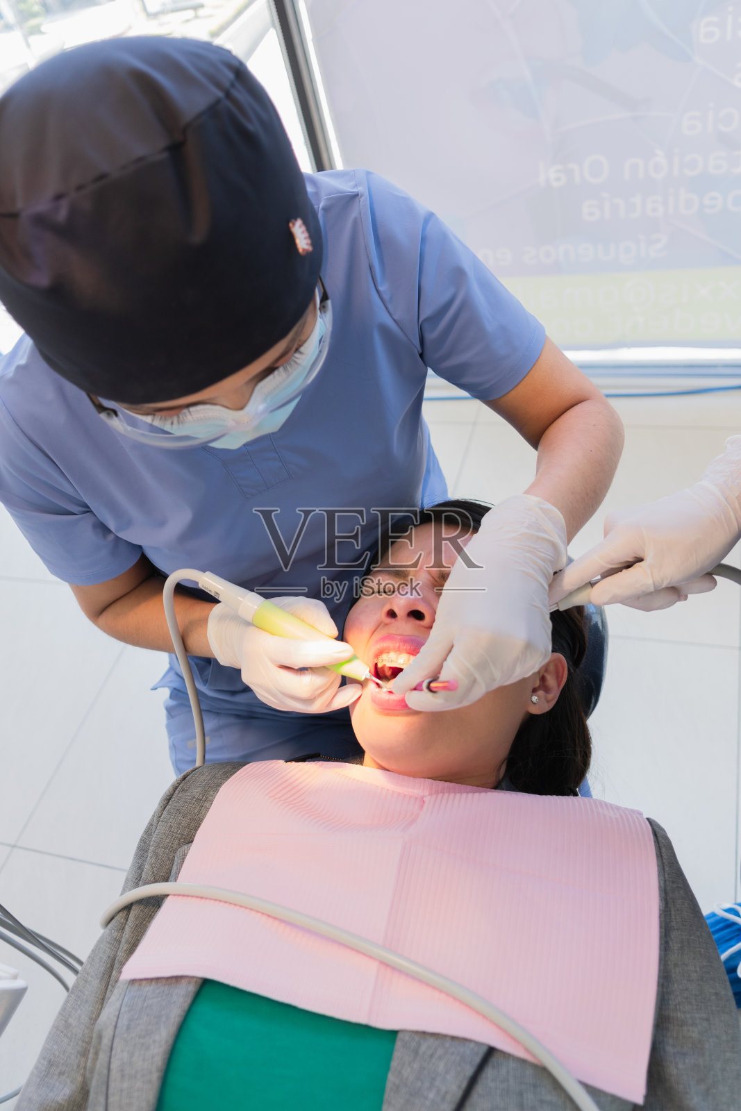 一位年轻的女牙医正在给一位女病人做牙科手术。照片摄影图片