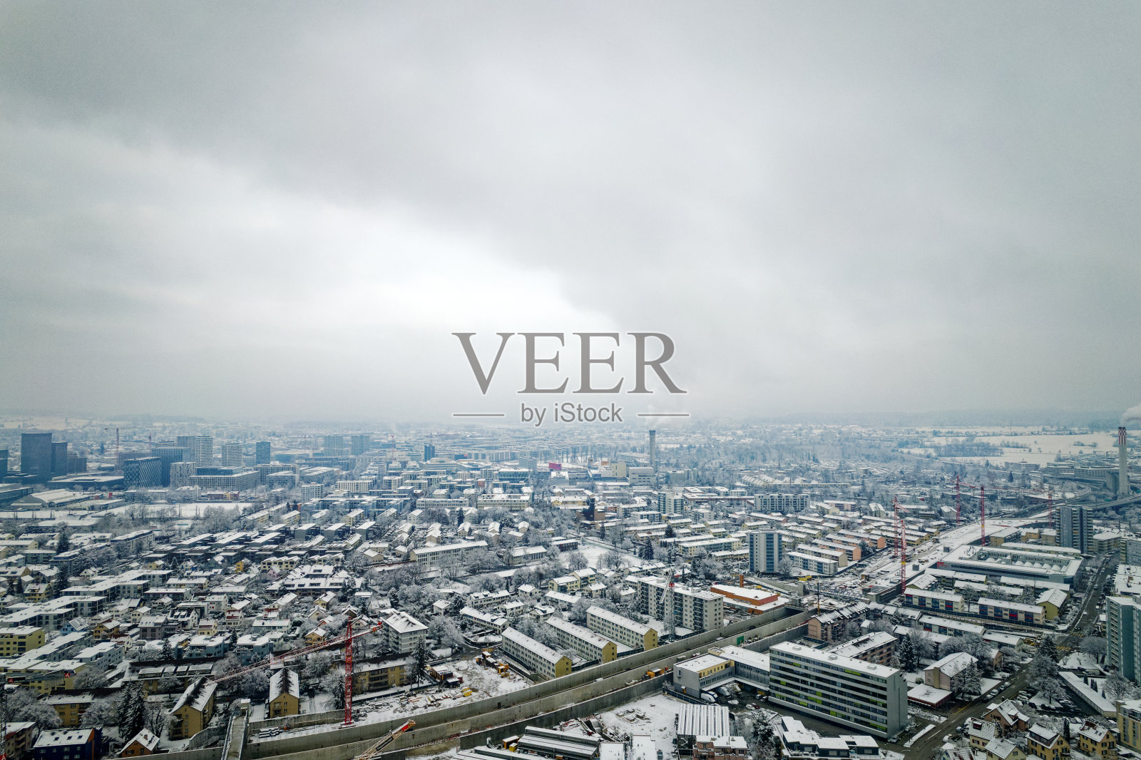 Aerial view over snow covered north part City of Zürich with skyline and gray cloudy winter sky on a snowy late autumn day.照片摄影图片