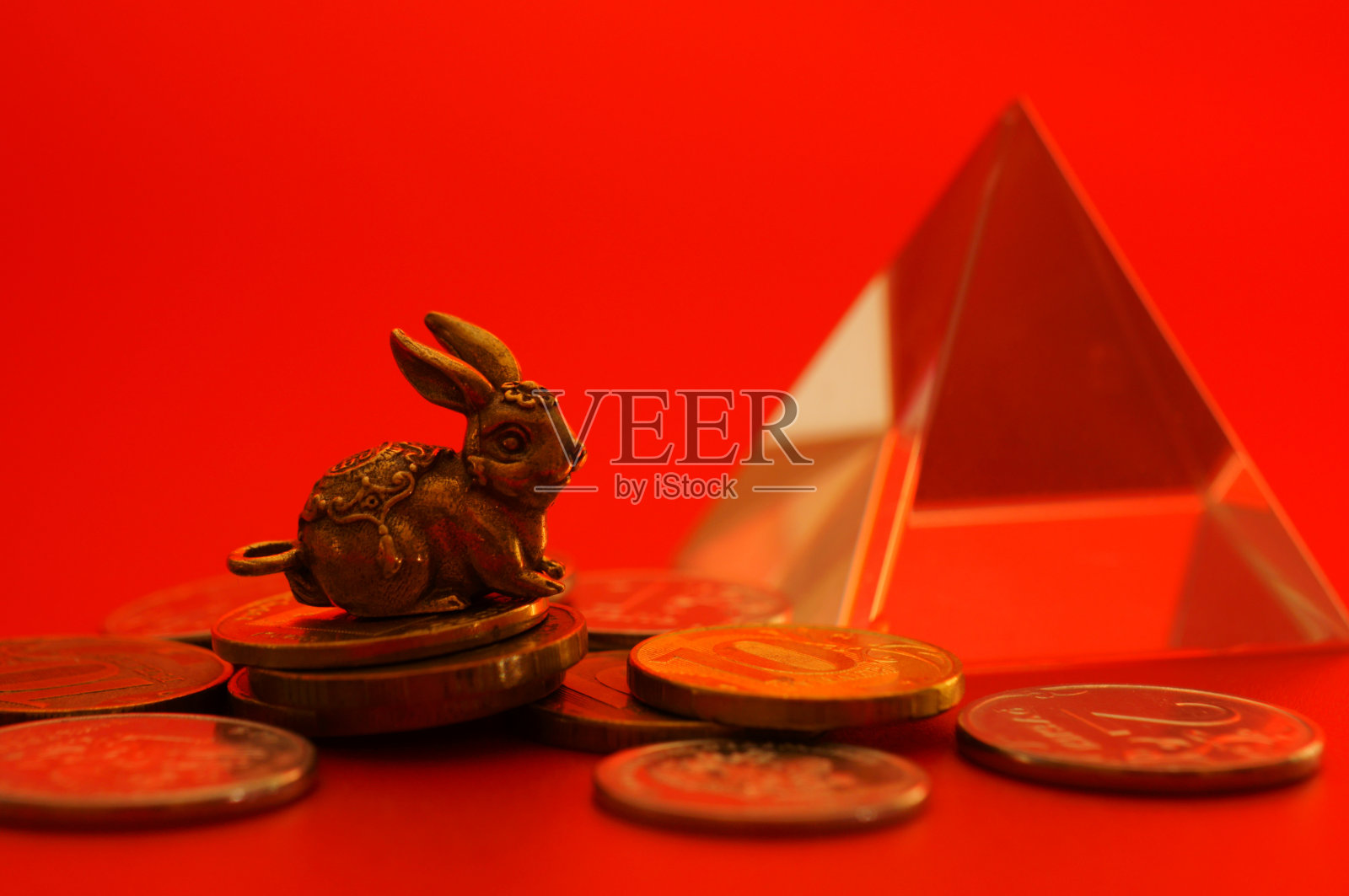 红色背景上有硬币的兔子雕像。照片摄影图片