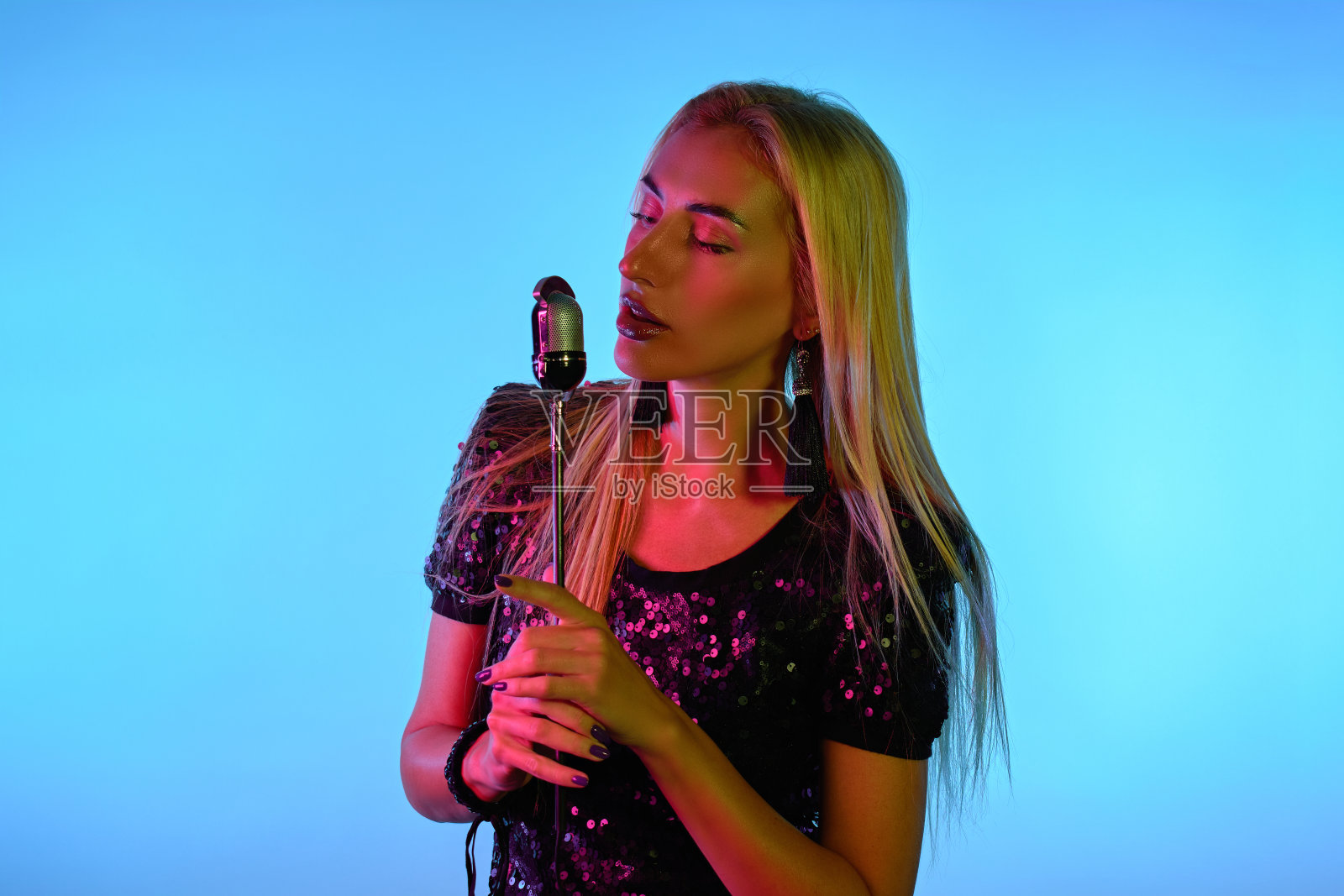 年轻性感的金发女歌手拿着麦克风照片摄影图片