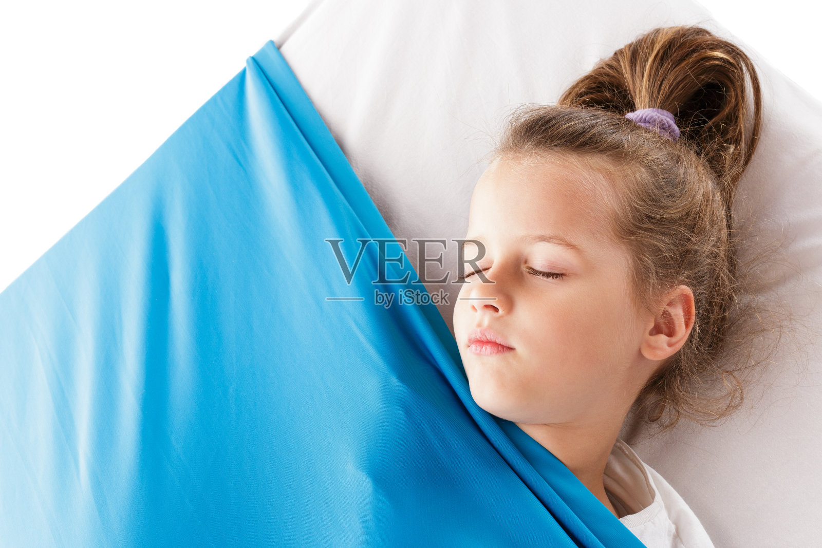 可爱的金发白人女孩睡在床垫下的蓝色舒适的毯子照片摄影图片