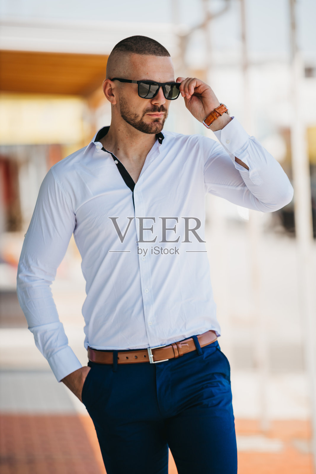 垂直拍摄的一个年轻人，穿着白色衬衫，戴着太阳镜照片摄影图片