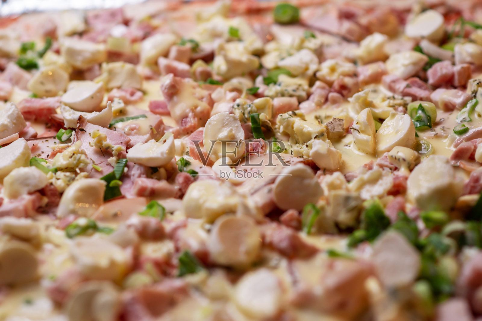 在烤盘上做自制披萨。披萨配马苏里拉芝士，香草和火腿。照片摄影图片