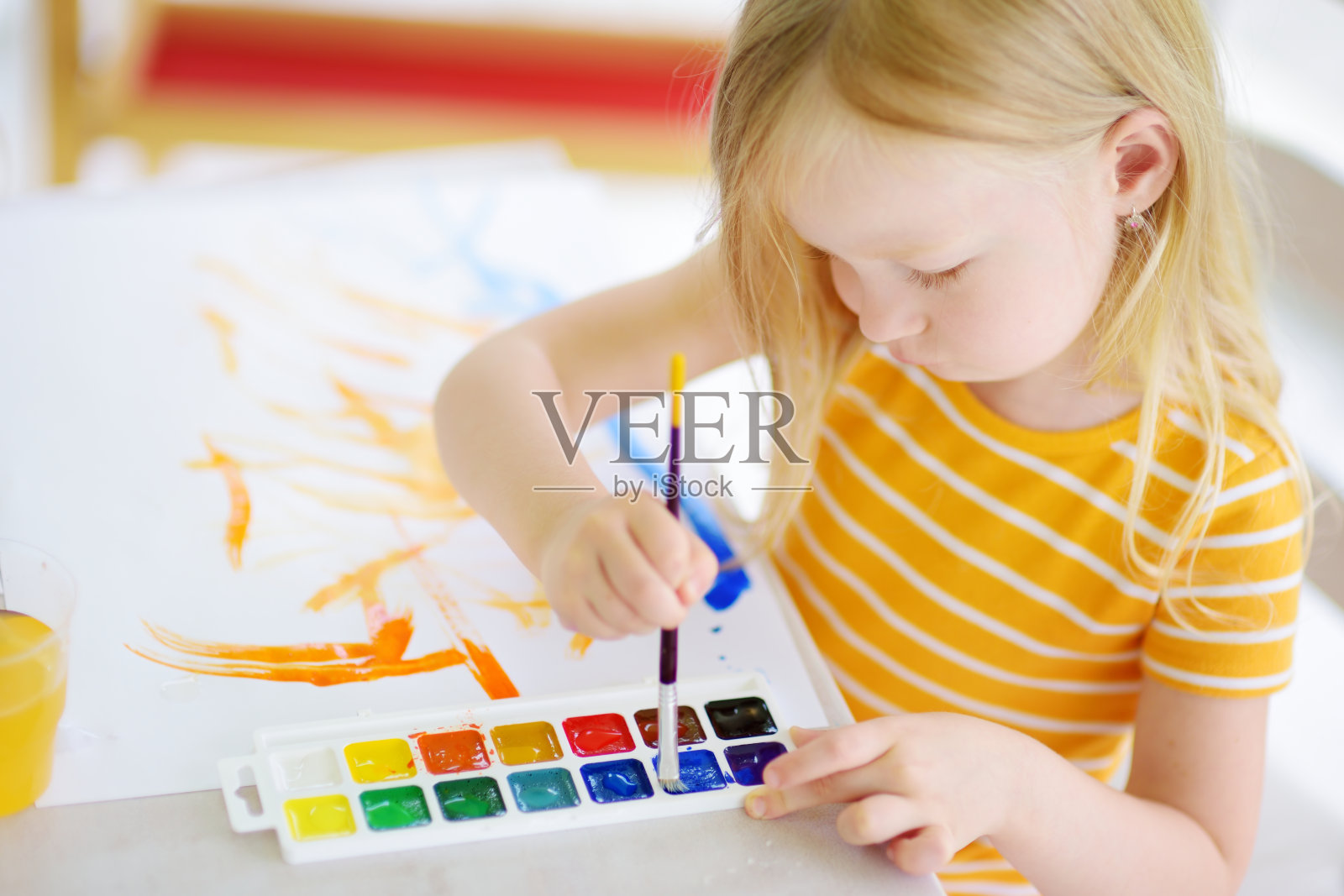 可爱的小女孩在日托中心用彩色颜料画画。有创造力的孩子在学校画画。照片摄影图片