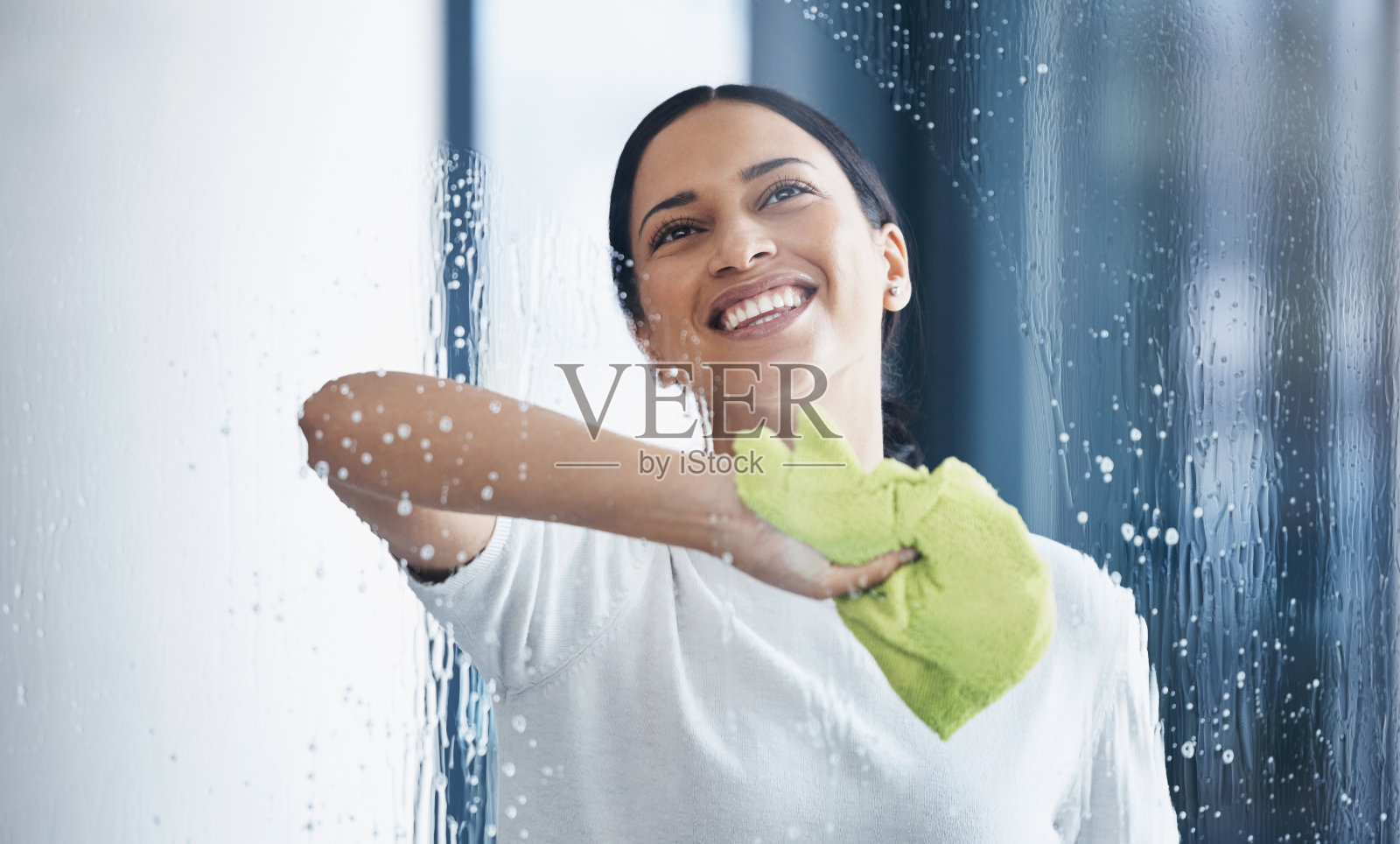 一名黑人妇女在办公室用布或抹布擦窗户时进行清洁、玻璃和卫生工作。清洁工、看门人或管家用肥皂和水清洗透明表面照片摄影图片