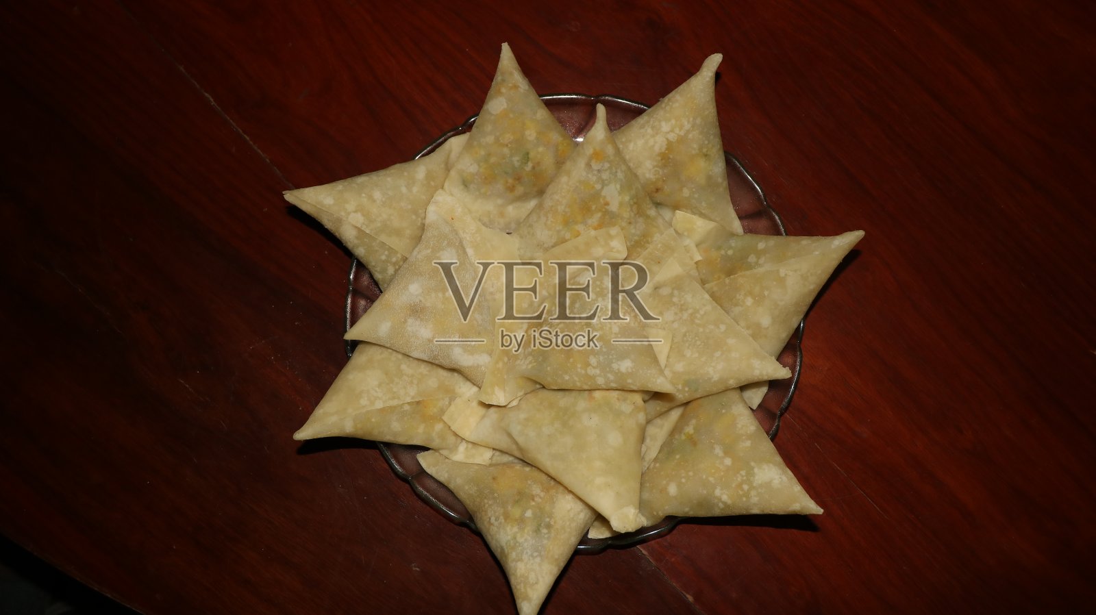 生的冷冻萨莫萨在盘子上的木桌孤立的形象照片摄影图片