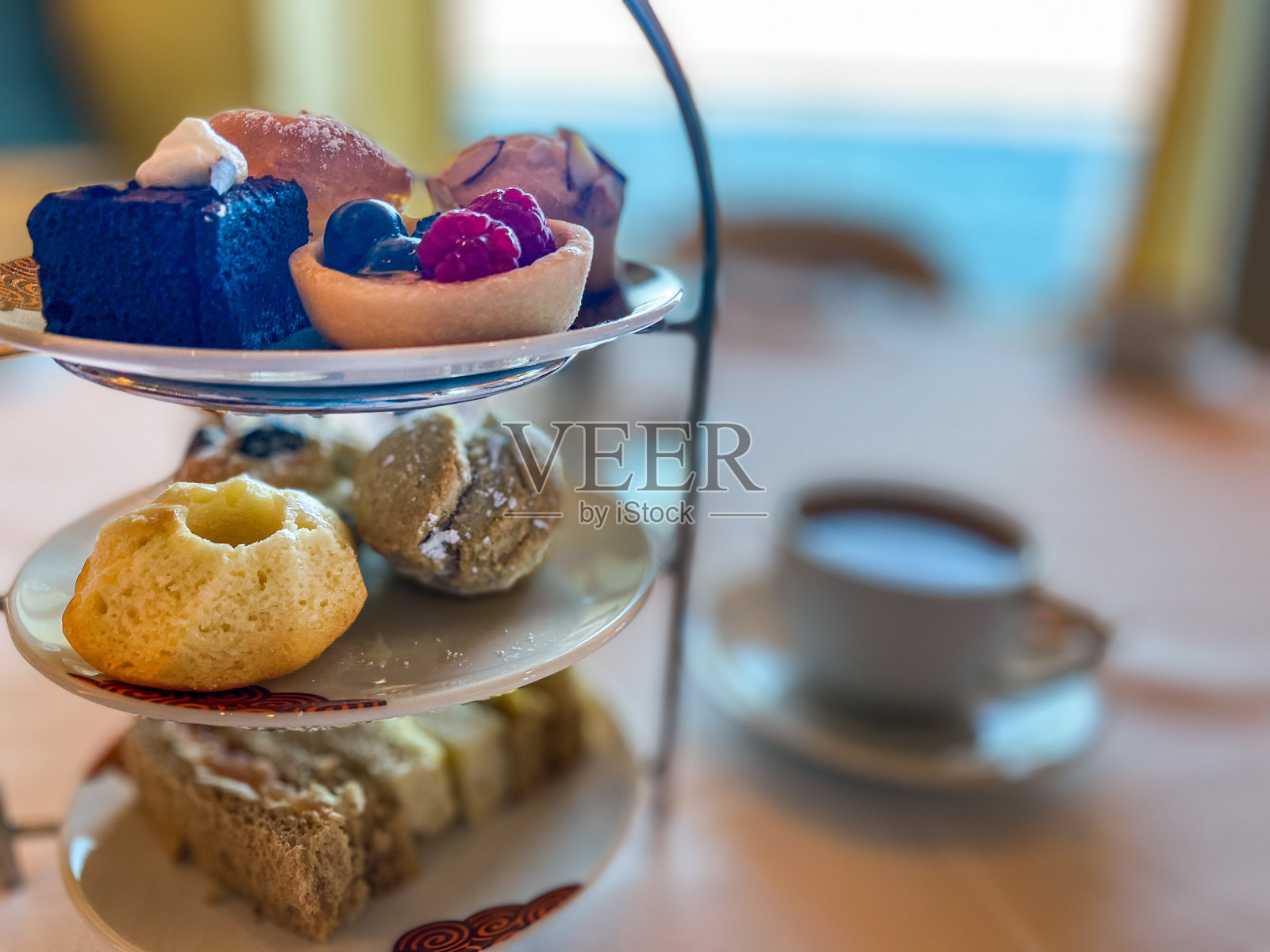 新鲜烤饼，果酱，美味的奶油，三明治和其他糕点在优雅的蛋糕架。这道菜是典型的英式下午茶或奶油茶的丰富传统。照片摄影图片