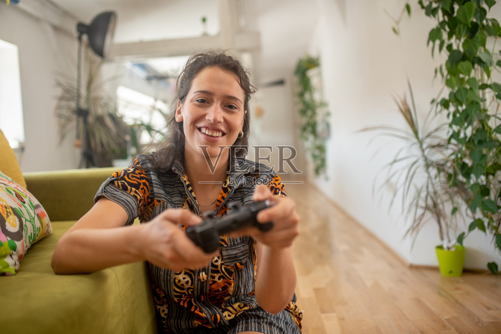 一个美丽的女人的肖像在家里玩电子游戏，有乐趣照片摄影图片