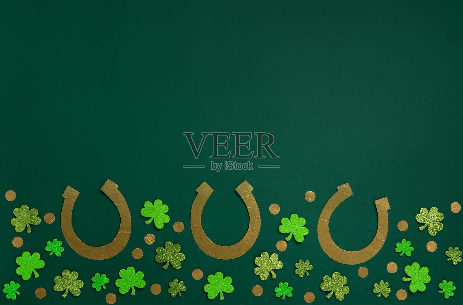 金色马蹄铁，金币和绿色背景三叶草叶子。照片摄影图片