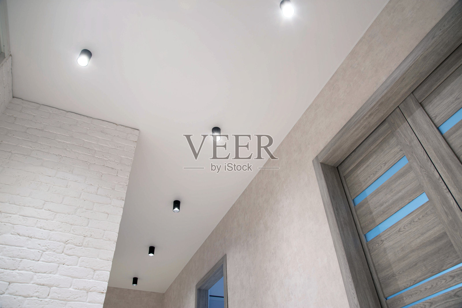 走廊的弹性天花板上有很多现代LED射灯。漂亮的灯光，灰色的室内门。室内照片摄影图片