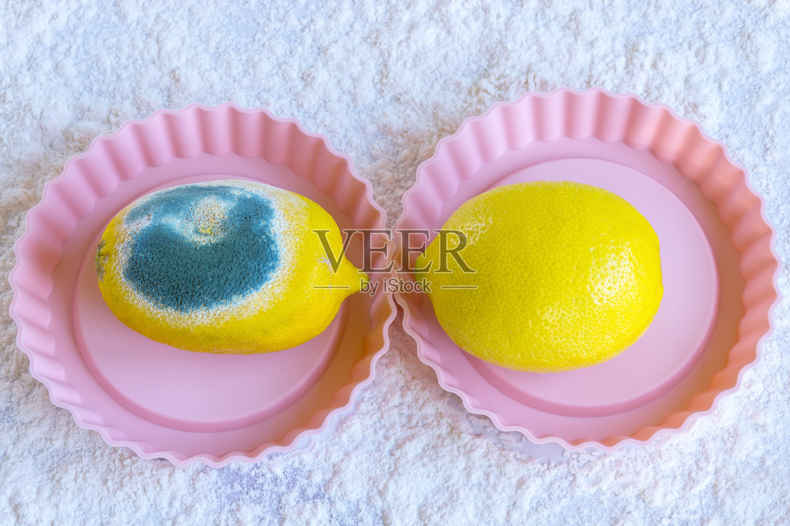 两个熟柠檬。其中一个坏了，长满了绿色的霉菌。照片摄影图片