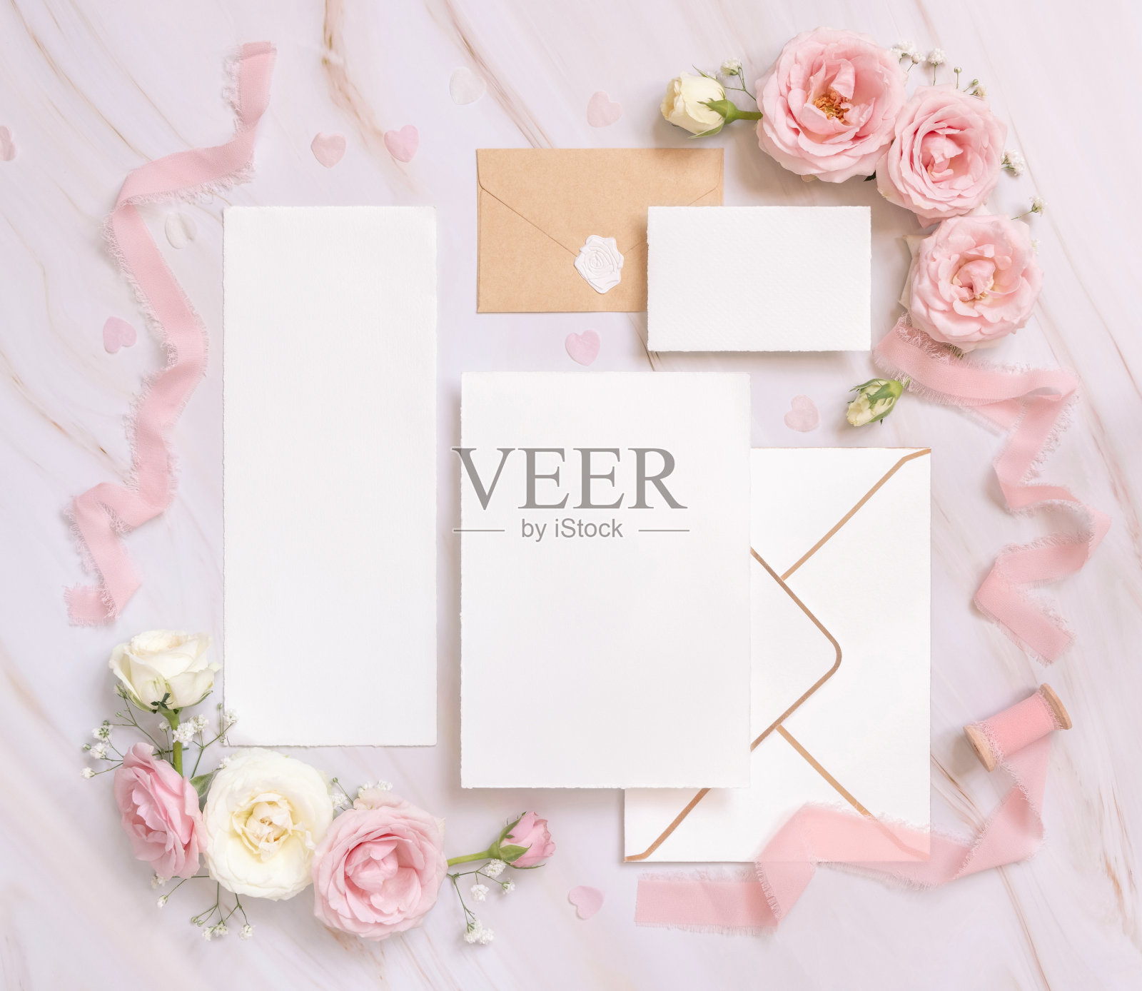 卡片和信封之间的粉红色玫瑰和粉红色绸带在大理石顶部视图，婚礼模型照片摄影图片