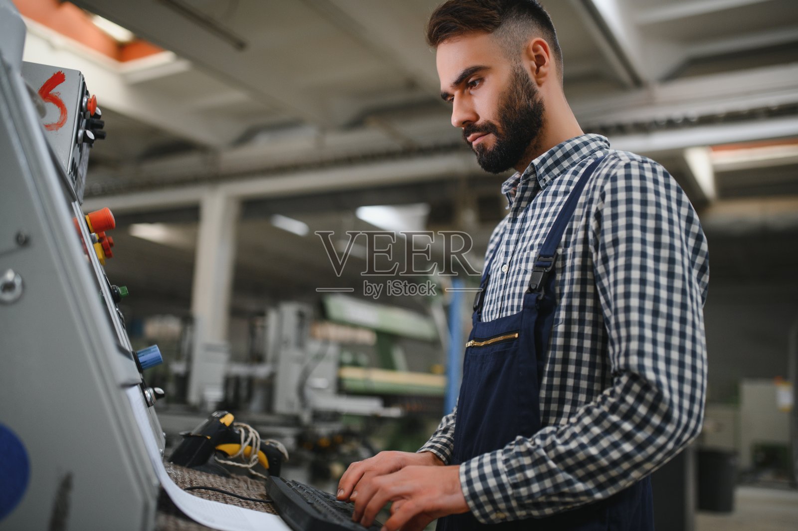 男性工厂工人在工厂内操作或维护机器时，应穿着安全制服，戴安全帽。照片摄影图片