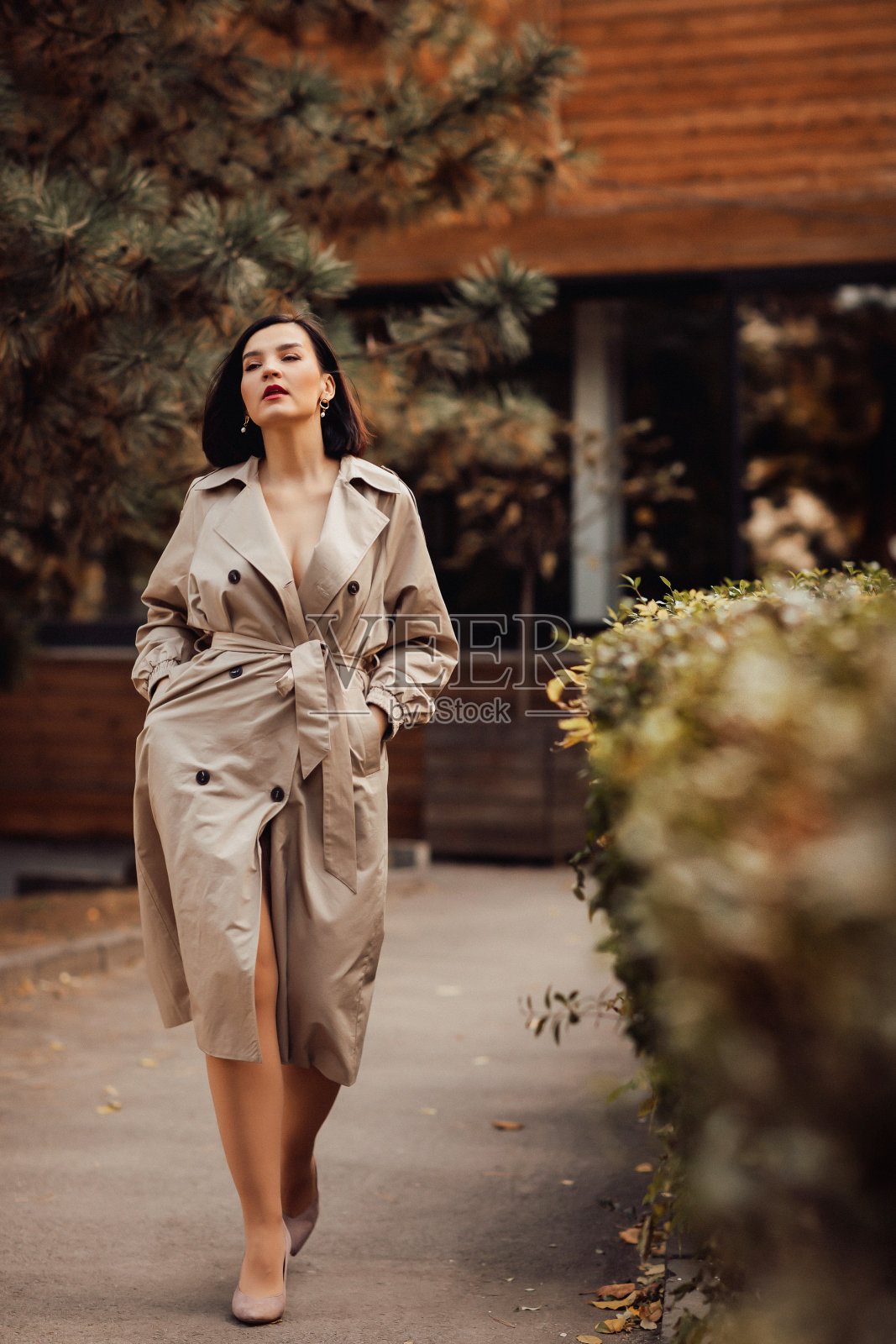 一个穿着秋衣的迷人黑发女子走在城市街道上。照片摄影图片