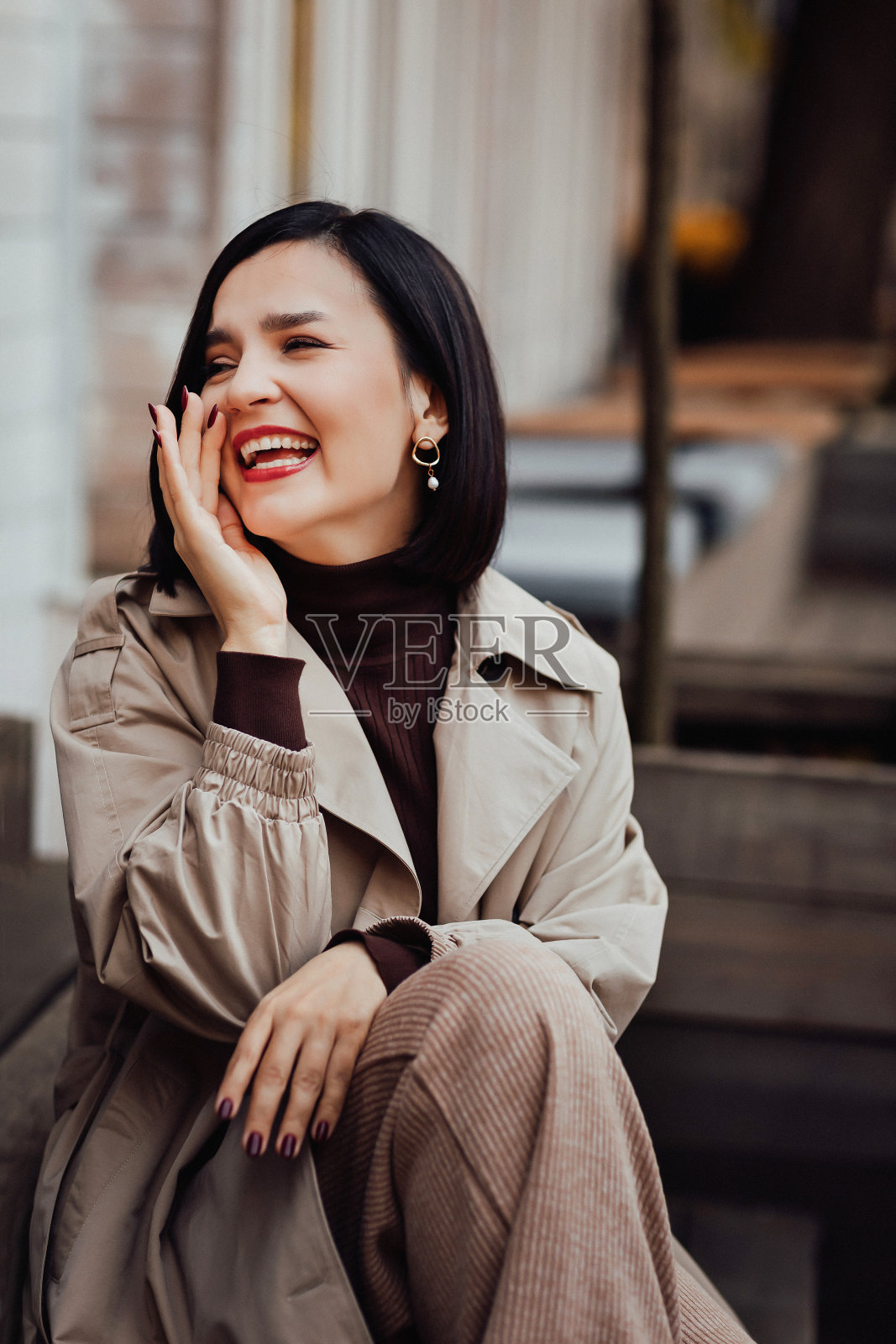 在城市街道上，一个穿着秋衣的快乐迷人的黑发女子的肖像。照片摄影图片