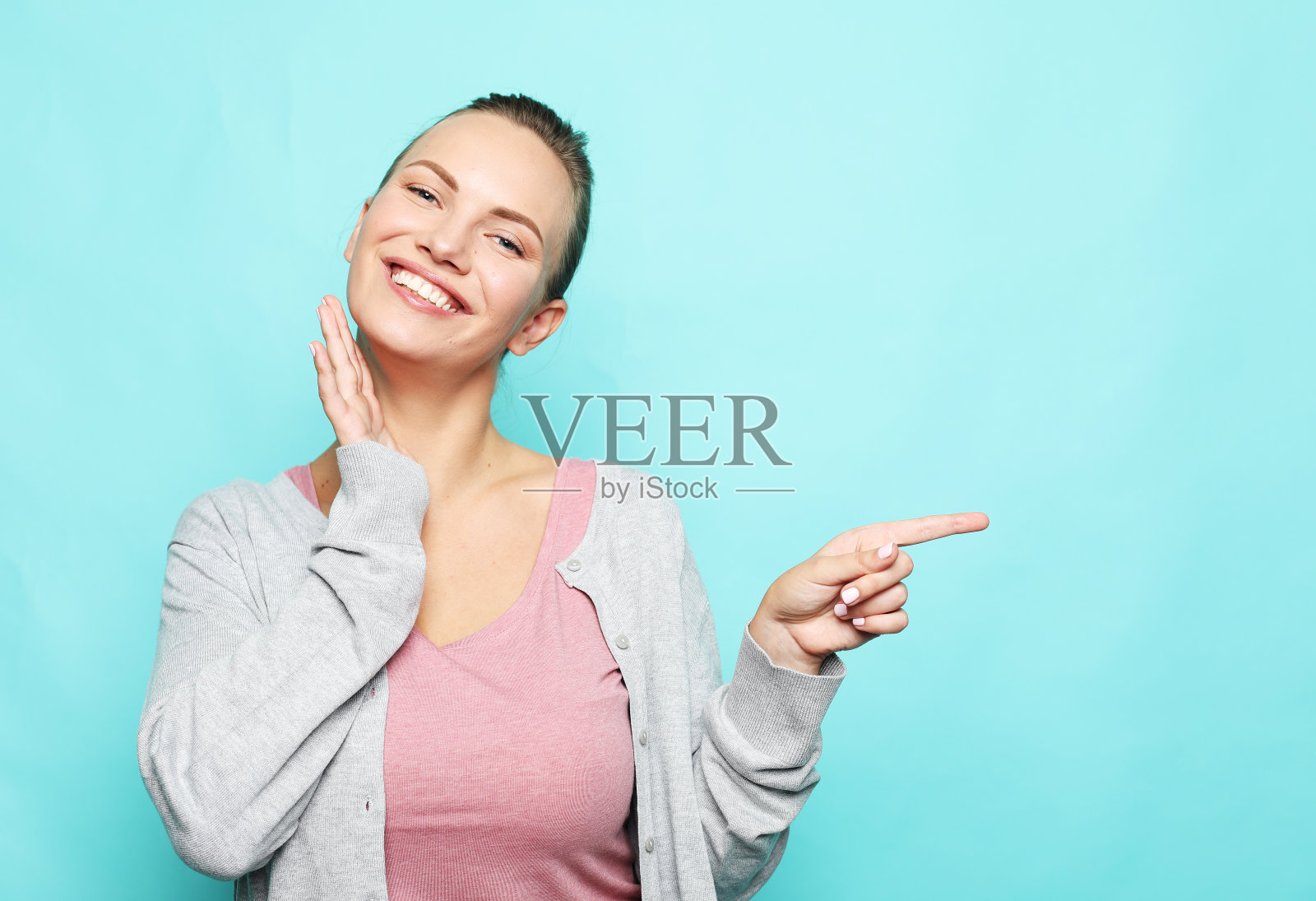 微笑的年轻女子指着空白复印空间一边手指照片摄影图片