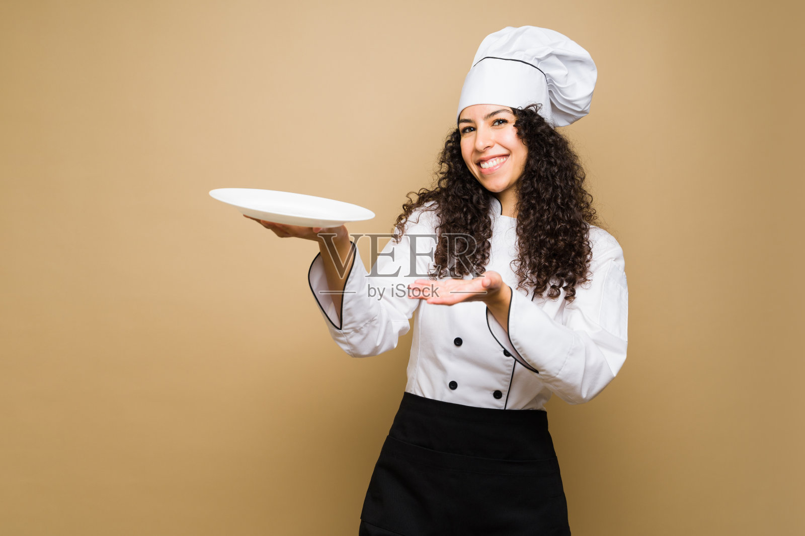 微笑的女厨师看起来很开心地提供食物照片摄影图片