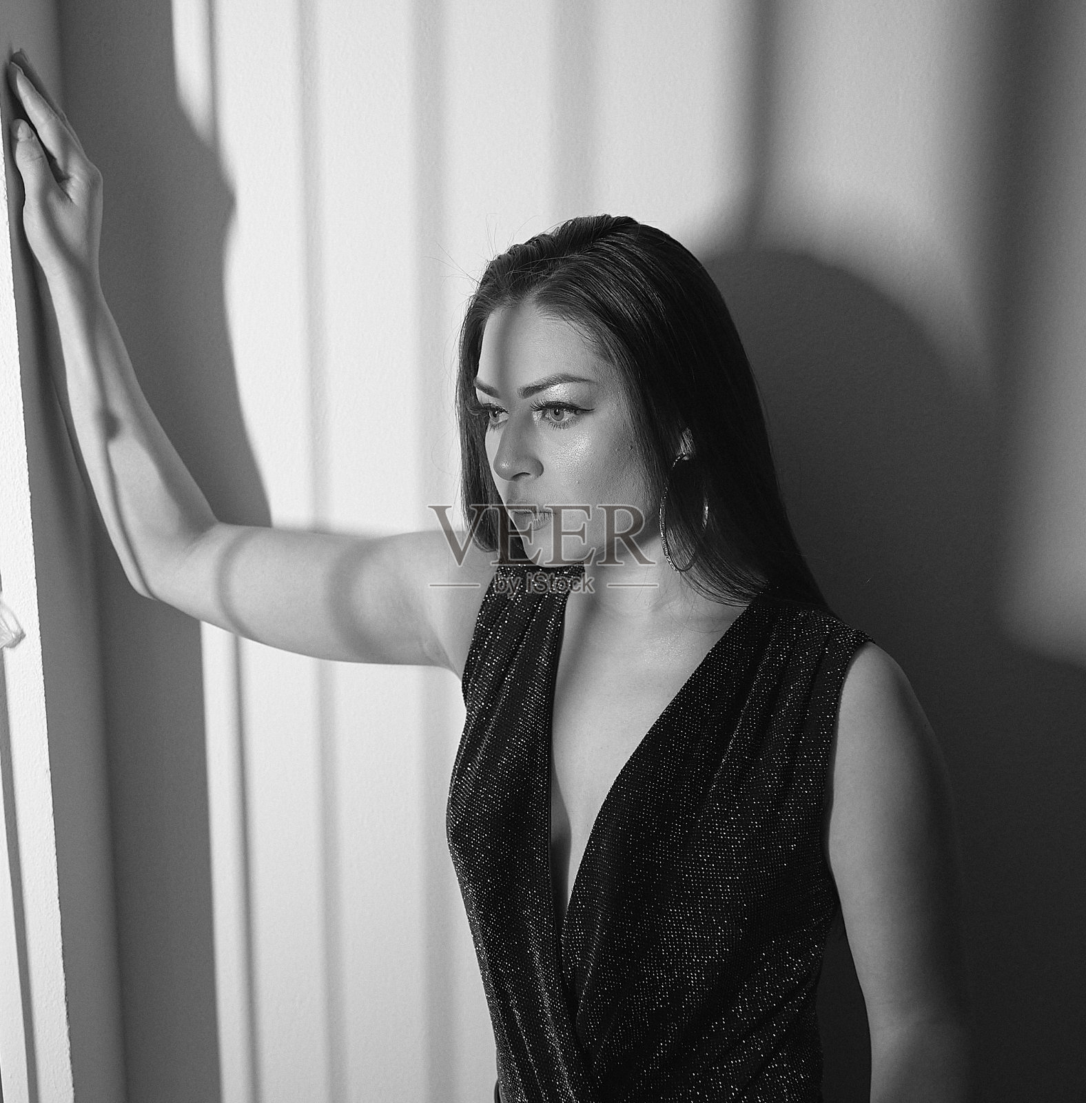 女人晚上在公寓里等着约会。摆出深思熟虑的姿势。照片摄影图片