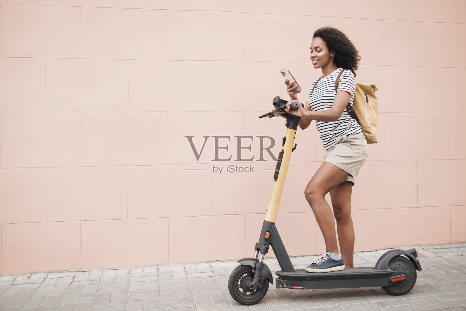 快乐的女人与电动滑板车使用智能手机在一个城市照片摄影图片