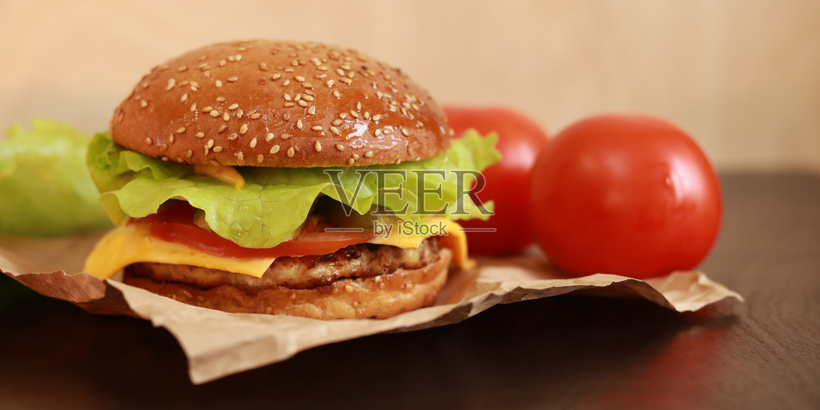 自制汉堡放在餐巾纸上，旁边有西红柿照片摄影图片