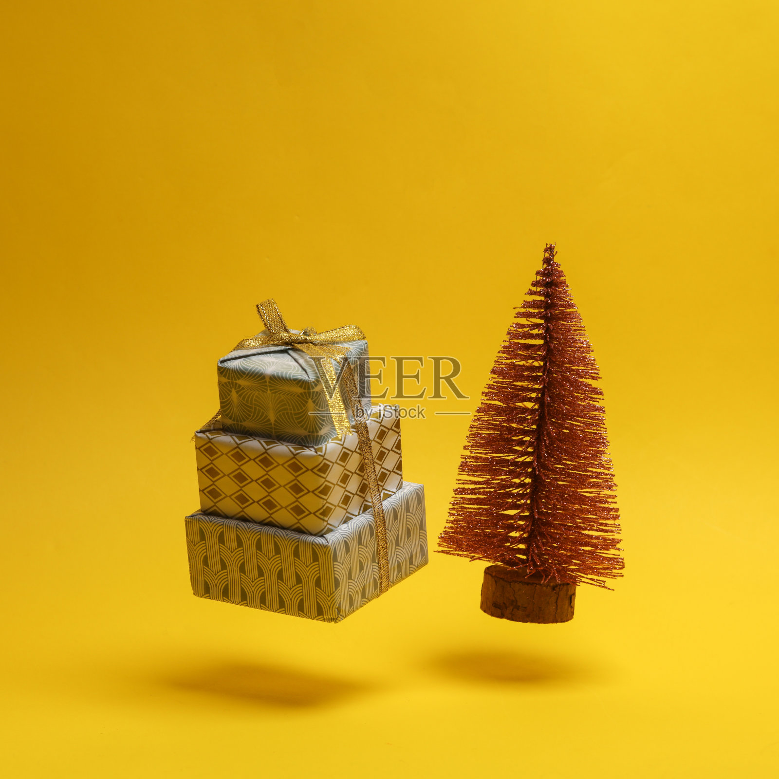 迷你圣诞树与礼品盒悬浮在黄色背景照片摄影图片