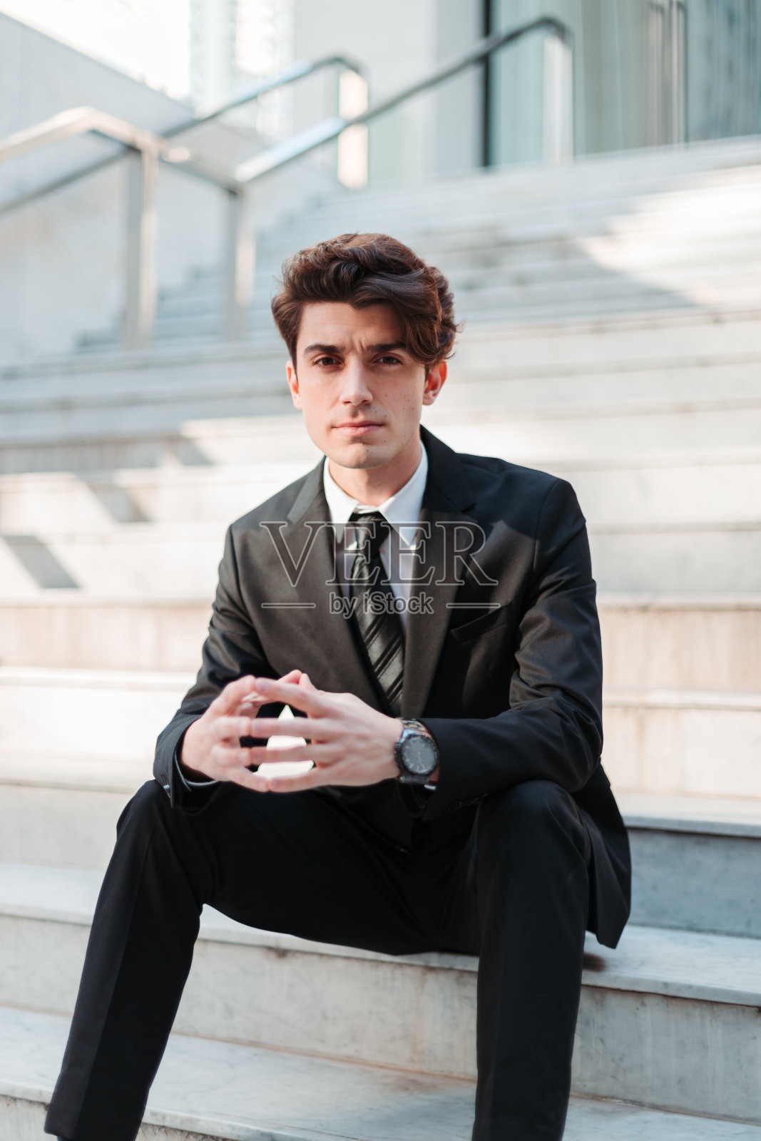 一个严肃的年轻白人男子穿着专业的垂直镜头坐在楼梯上照片摄影图片