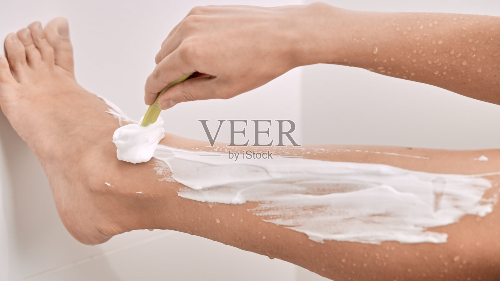 女性手握剃刀脱毛时的女性腿照片摄影图片