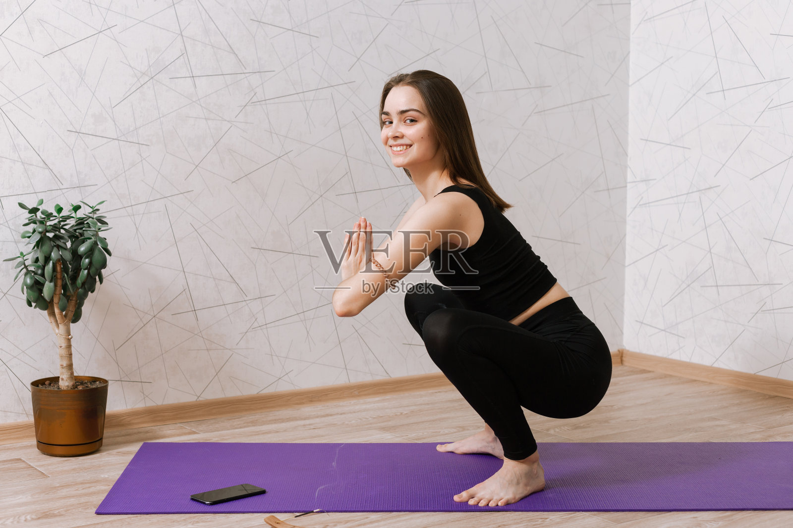 正面女性在客厅的运动垫上做瑜伽照片摄影图片