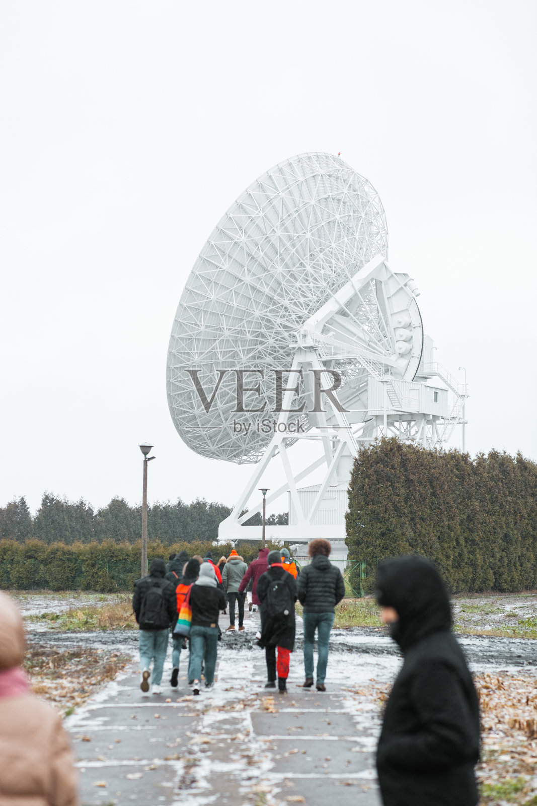 一群人面对着一个巨大的卫星天线照片摄影图片
