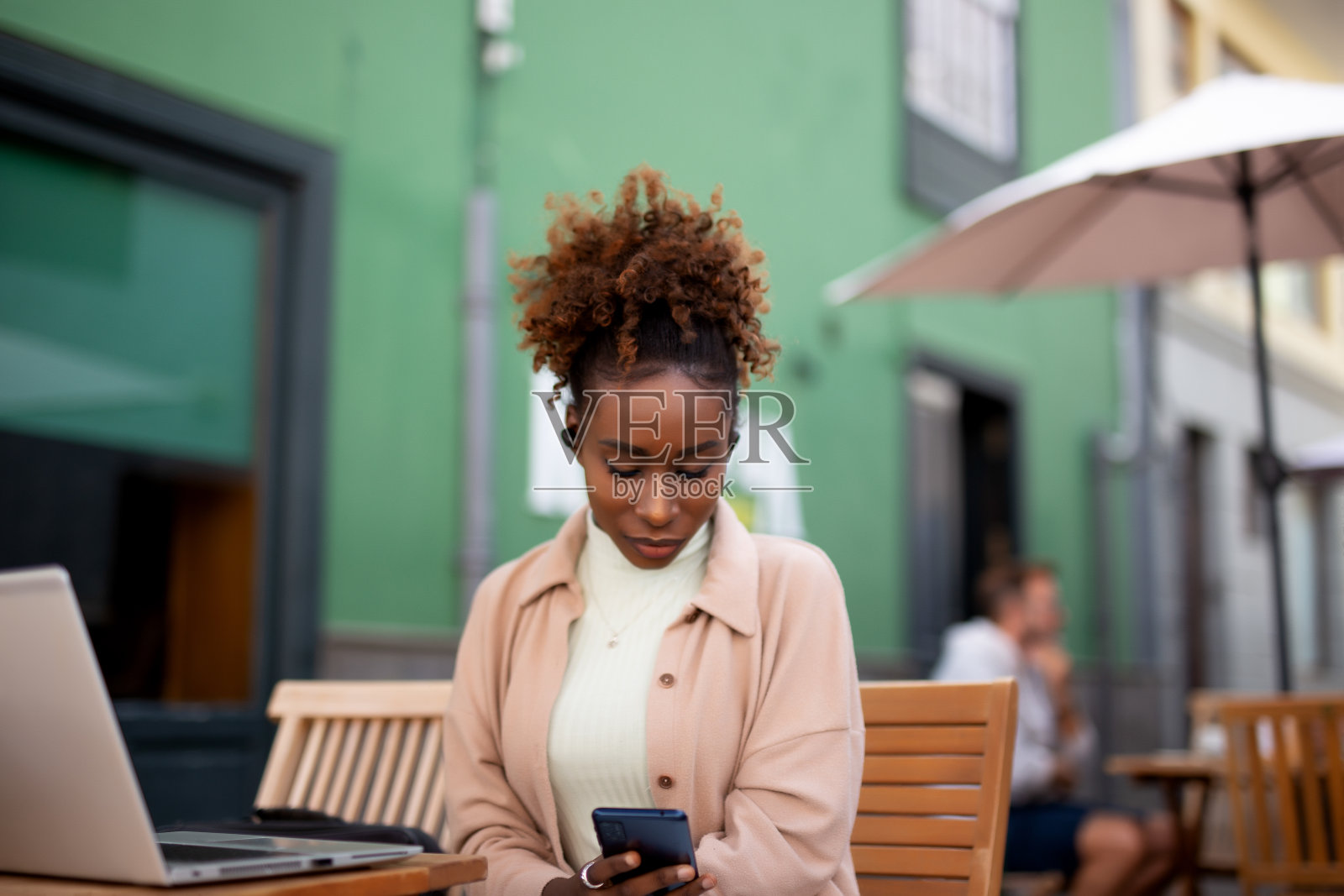 年轻女子过马路，在城市里戴着耳机听音乐照片摄影图片